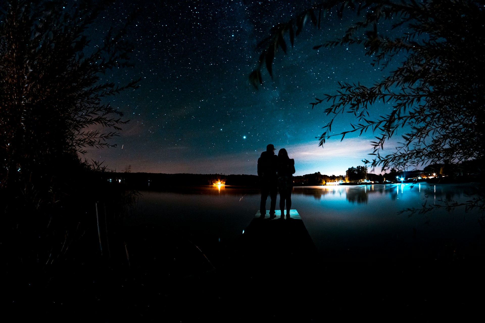 Una joven pareja admira las estrellas desde un embarcadero en un atardecer pintoresco | Fuente: Unsplash