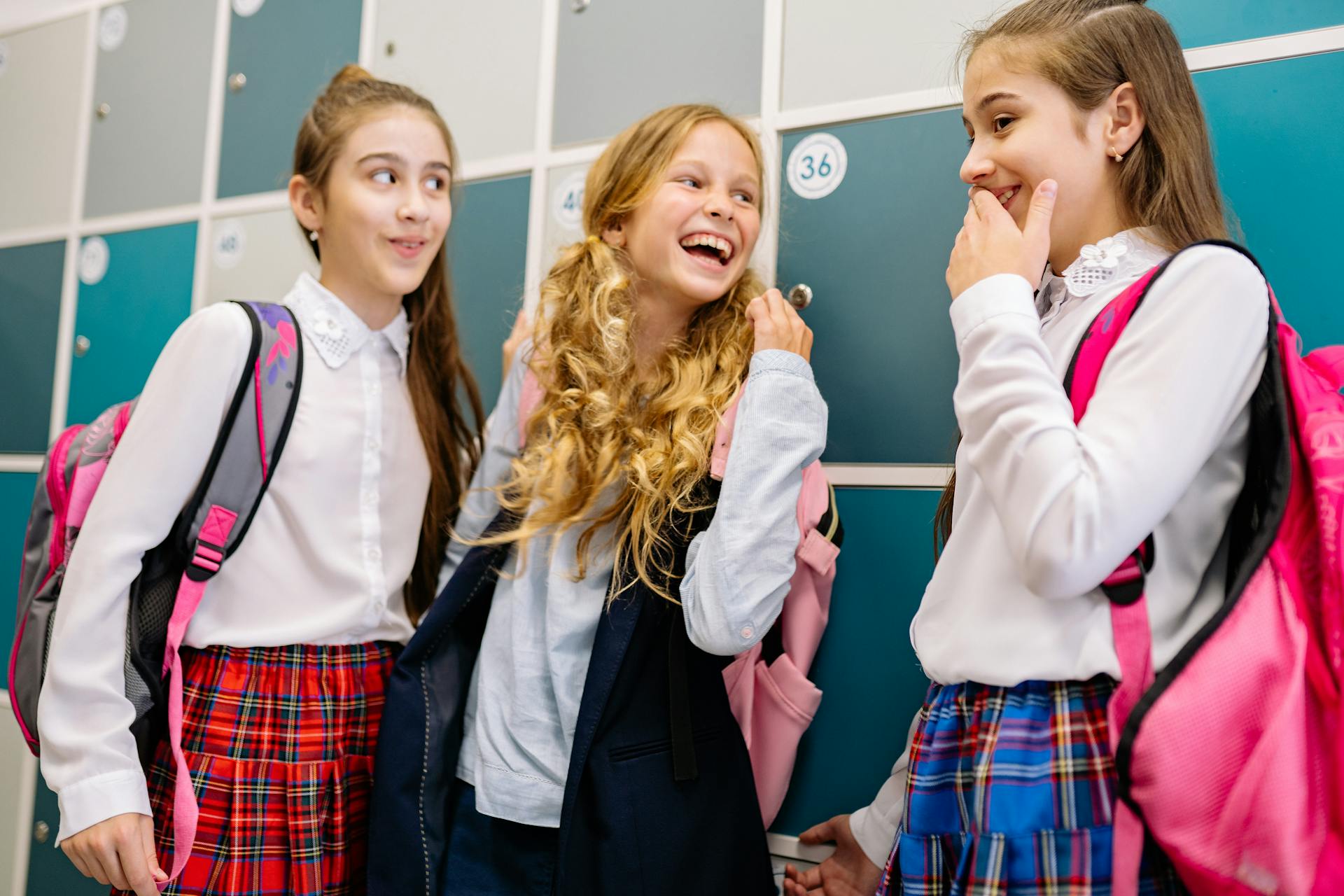 Tres alumnas compartiendo una risa frente a sus casilleros | Fuente: Pexels