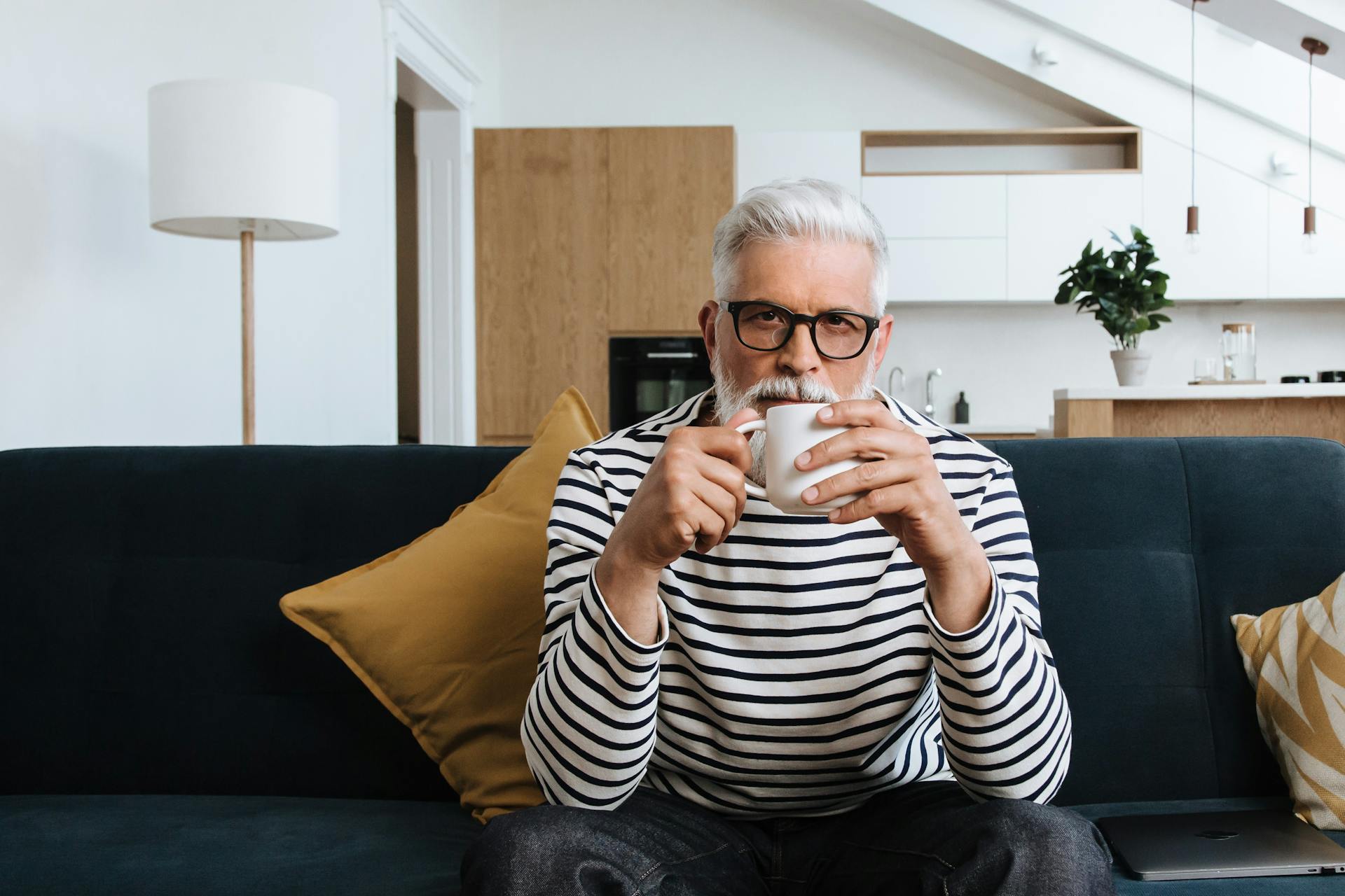 Un hombre mayor tomando el té sentado en un sofá | Fuente: Pexels