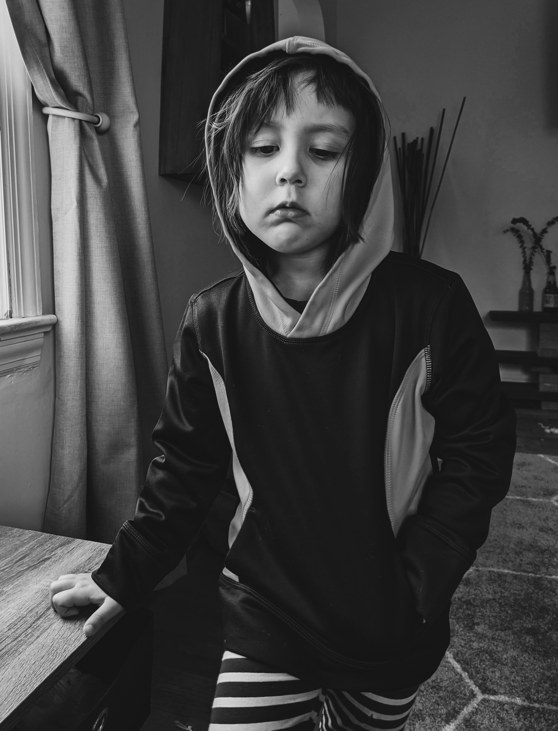 Toma en escala de grises de un niño pensativo | Fuente: Unsplash