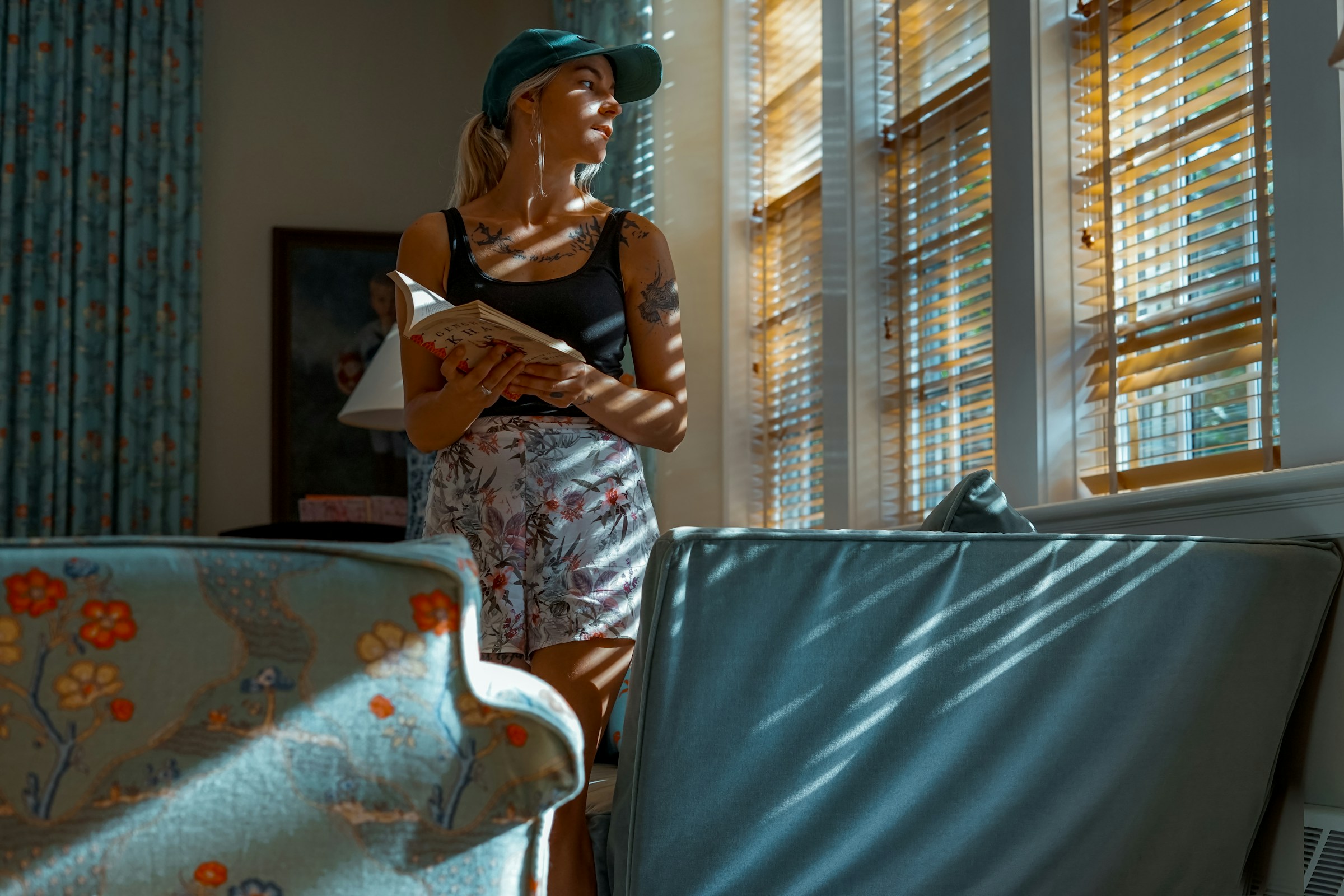 Una mujer mirando por la ventana mientras sostiene un libro | Fuente: Unsplash
