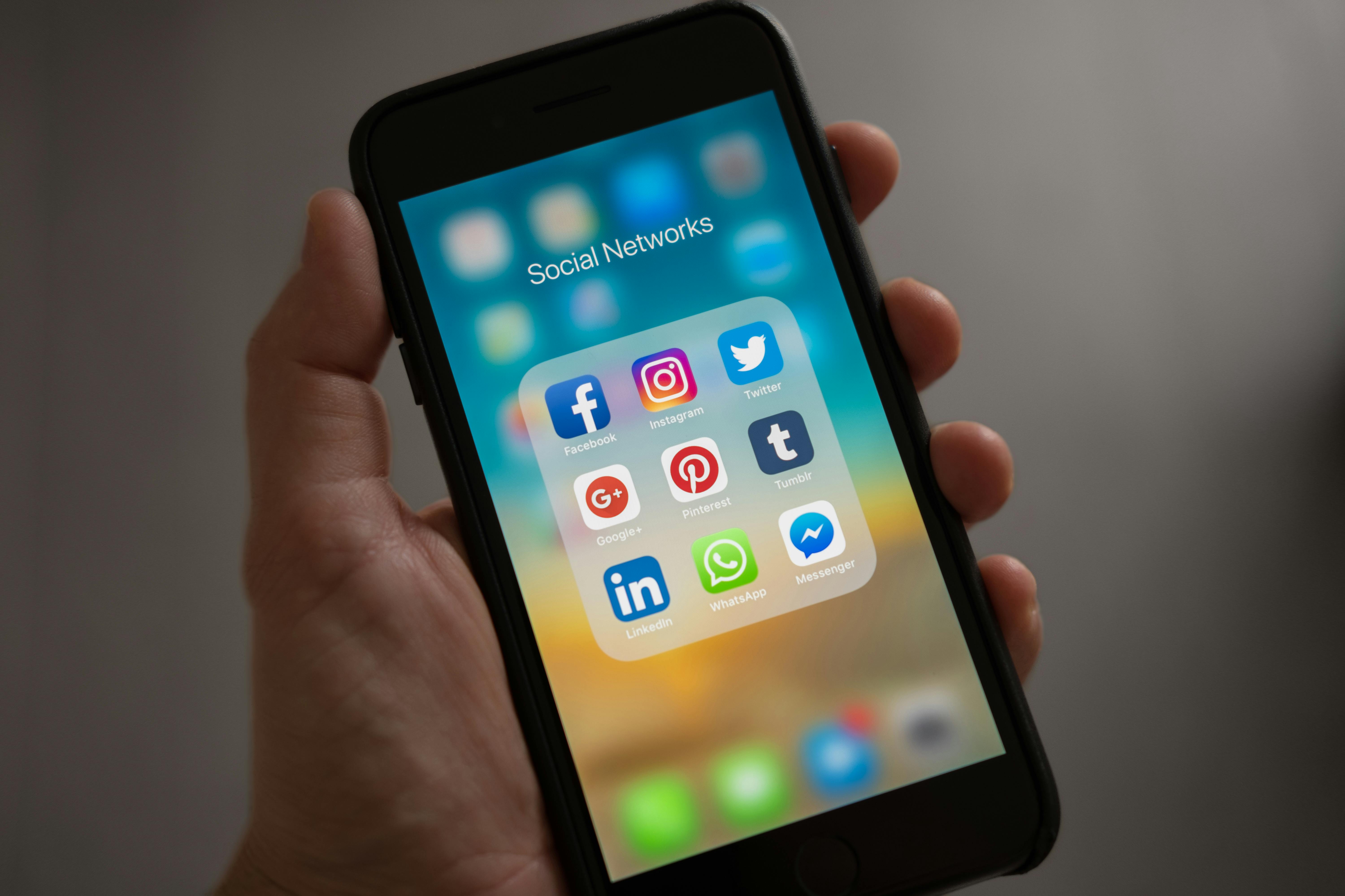 Una persona con el móvil abierto en una carpeta de redes sociales | Fuente: Pexels