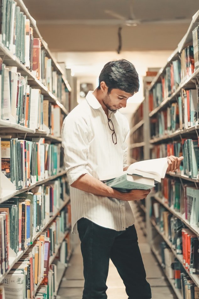 Un chico leyendo un libro en una biblioteca | Fuente: Unsplash