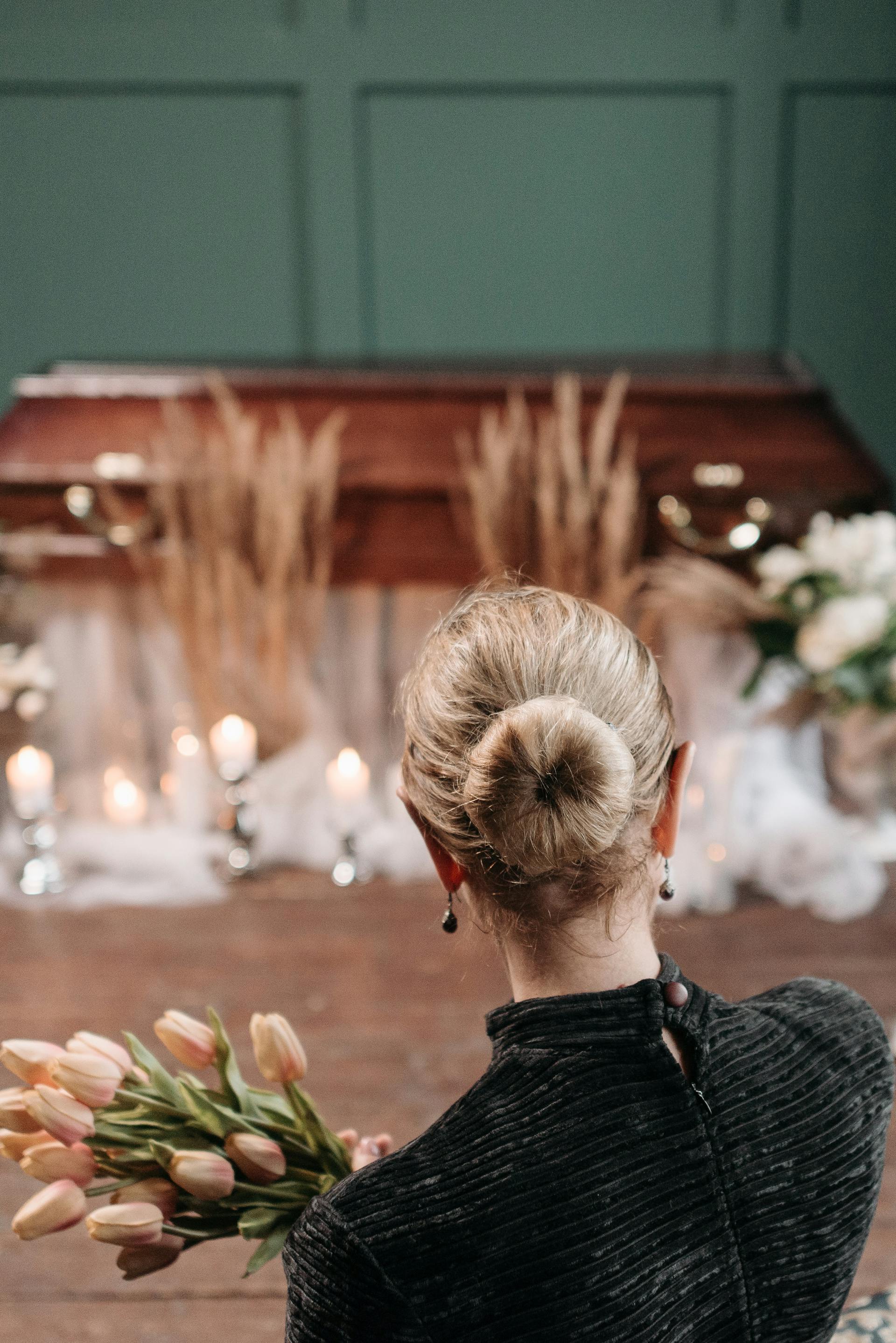 Una mujer con un ramo de flores delante de un ataúd | Fuente: Pexels