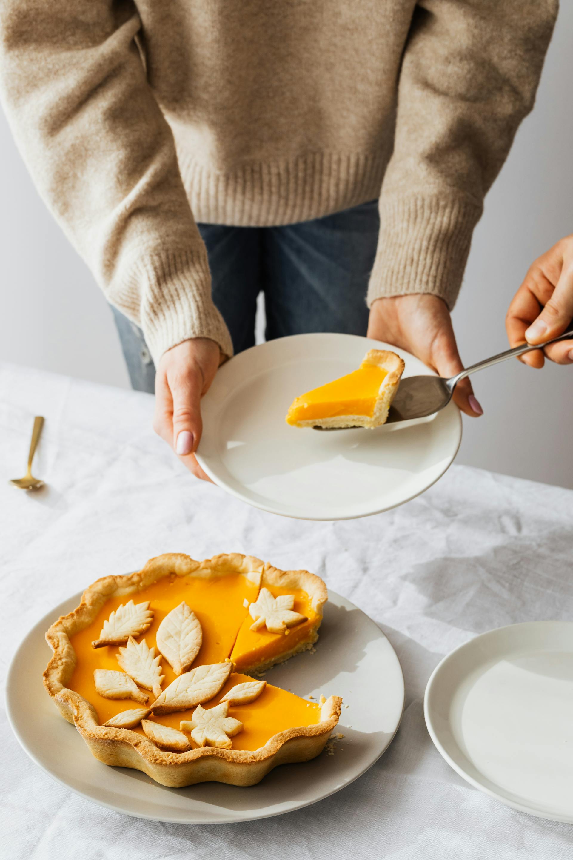 Un trozo de tarta de limón en un plato sostenido por una persona | Fuente: Pexels