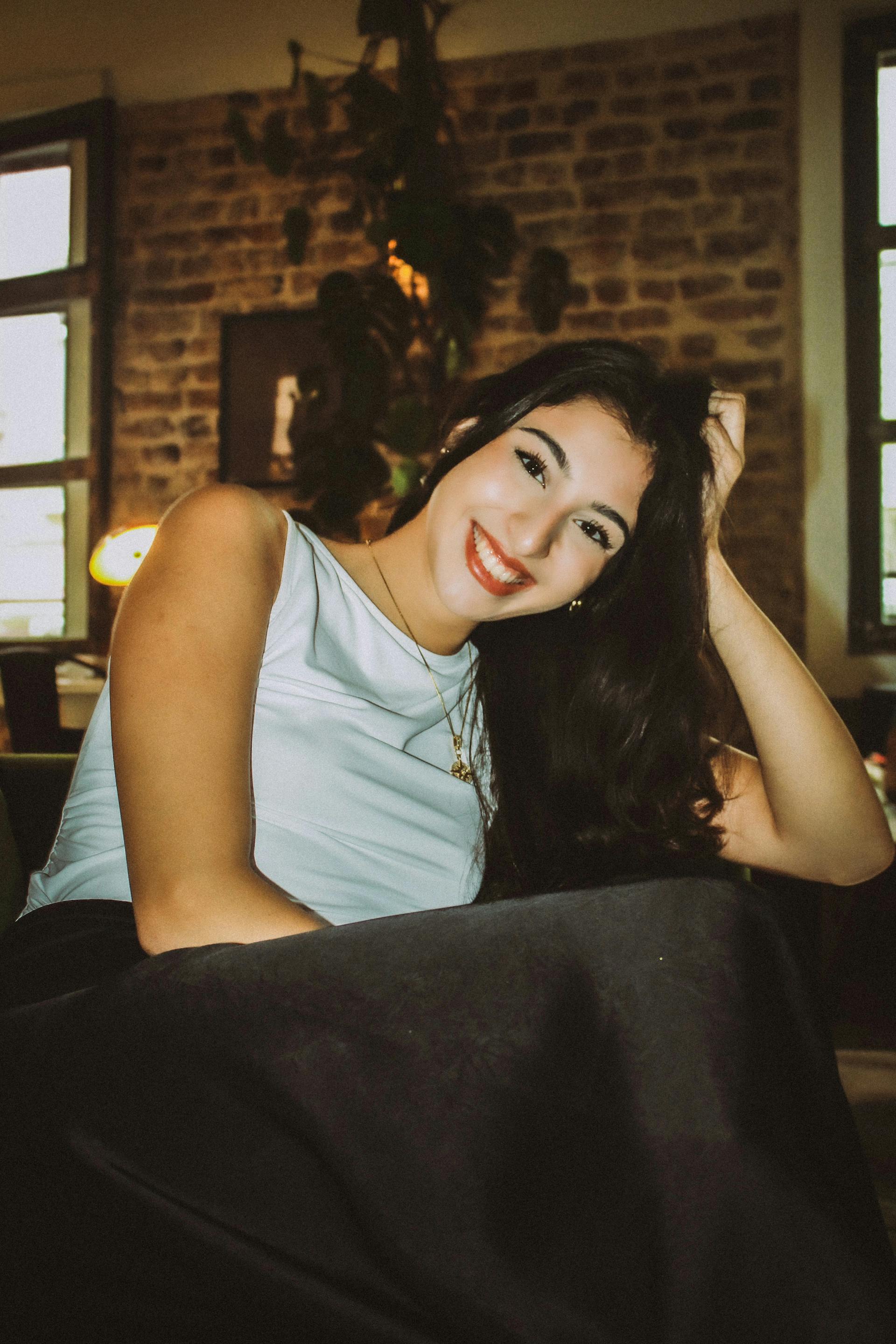 Una mujer con el pelo largo sentada en una silla y sonriendo | Fuente: Pexels