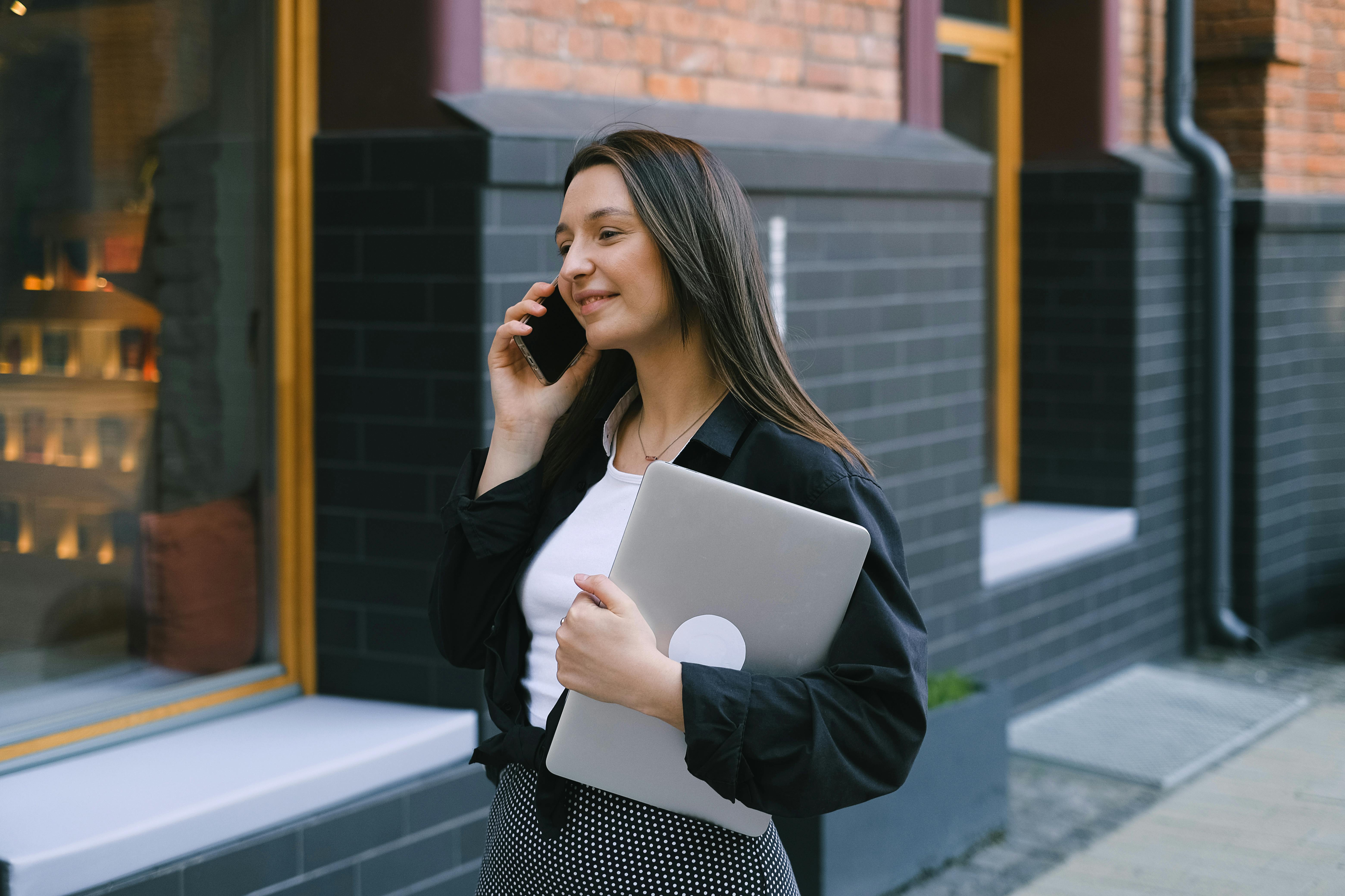 Mujer caminando por la calle mientras atiende una llamada telefónica | Fuente: Pexels