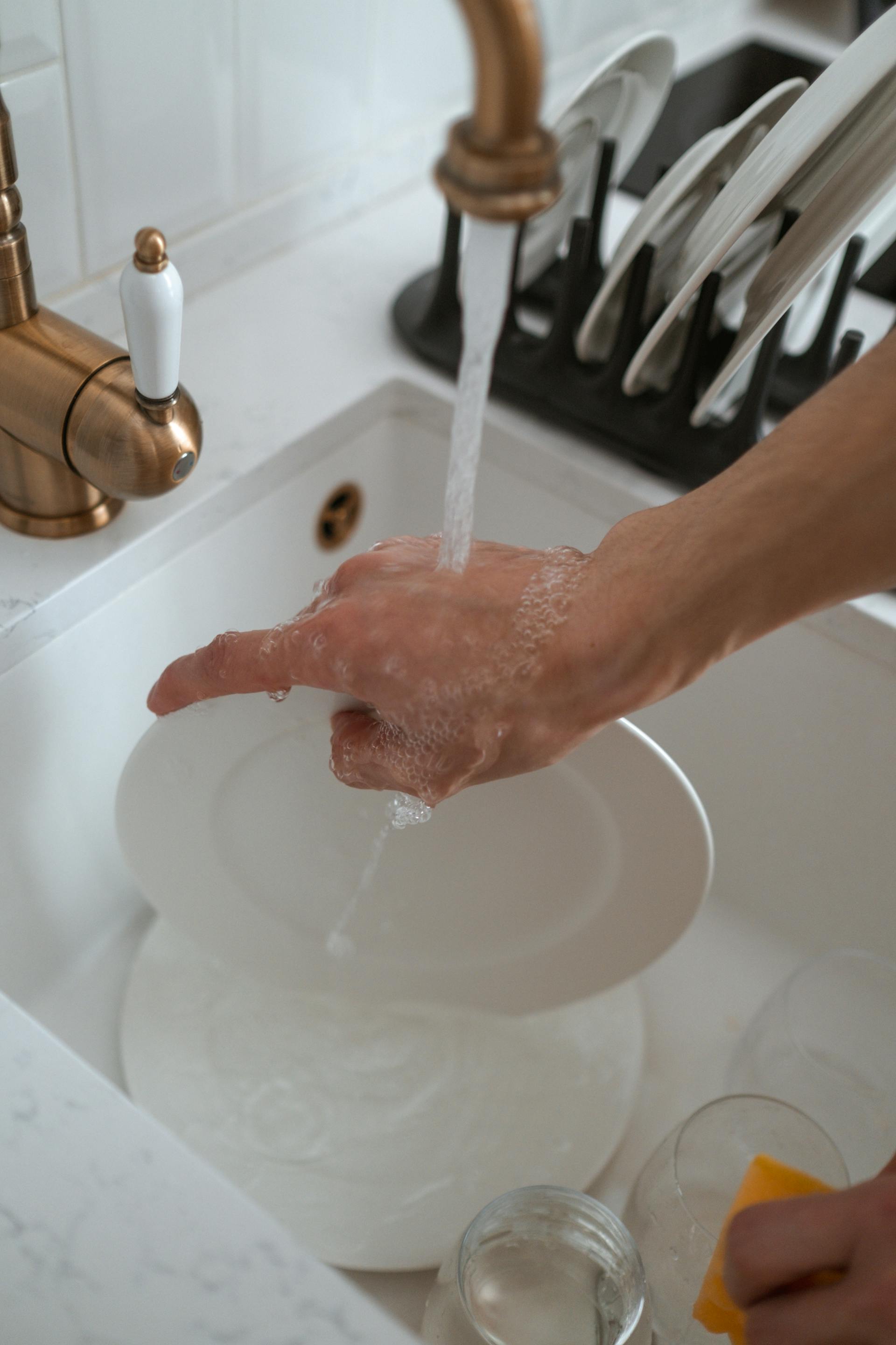Primer plano de una mujer fregando platos | Fuente: Pexels