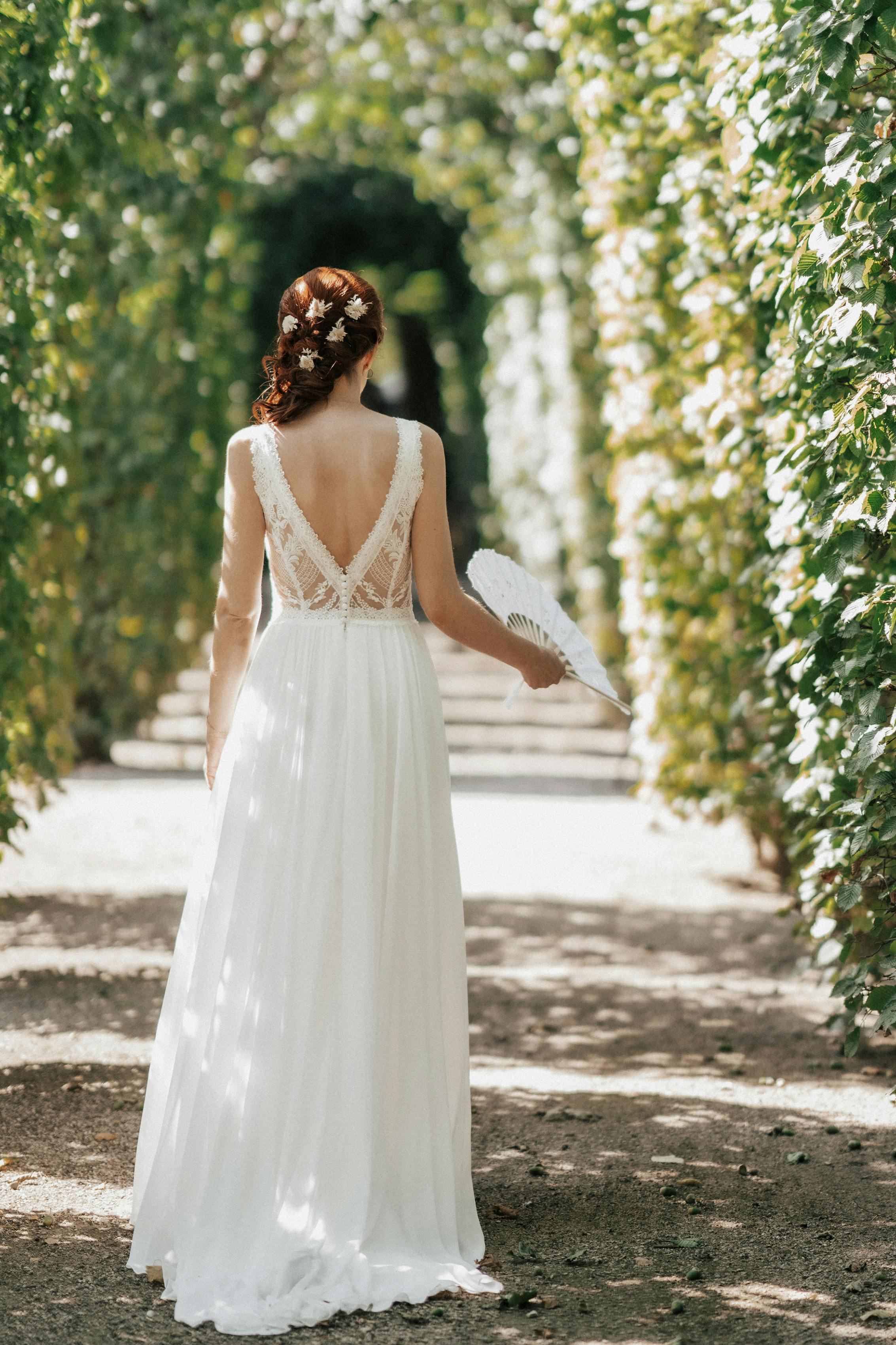 Novia con un elegante vestido de encaje en el arco del jardín | Fuente: Pexels