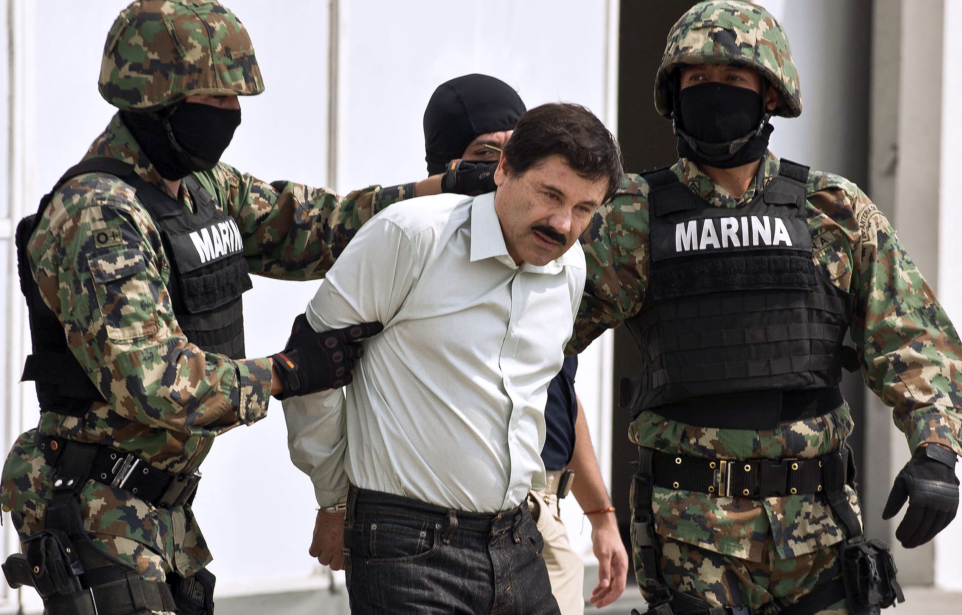 El narcotraficante mexicano Joaquín Guzmán Loera, alias "El Chapo Guzmán" (C), es escoltado por marines mientras es presentado a la prensa el 22 de febrero de 2014 en Ciudad de México. | Fuente: Getty Images