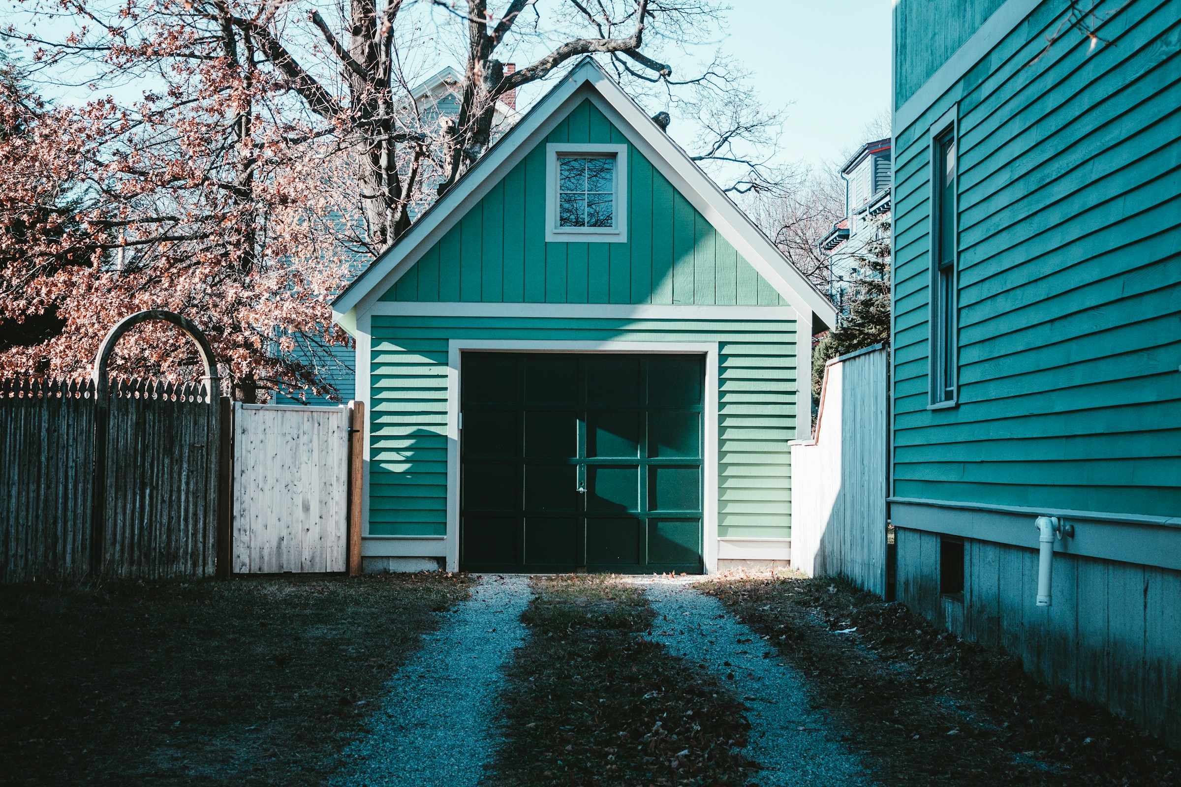 Una casa y un garaje de color verde azulado en un patio trasero | Fuente: Unsplash