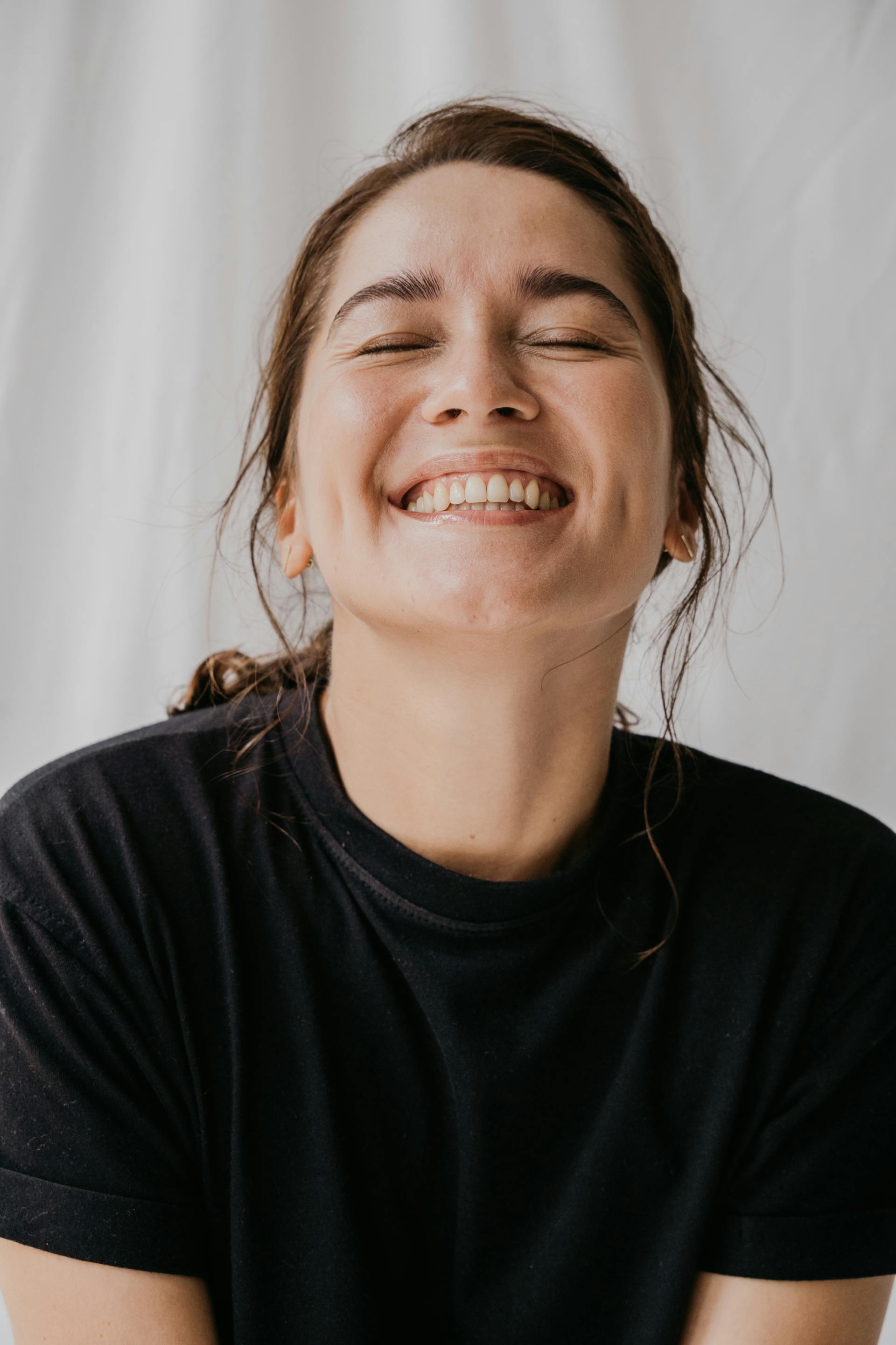 Una mujer sonriendo con los ojos cerrados | Fuente: Pexels