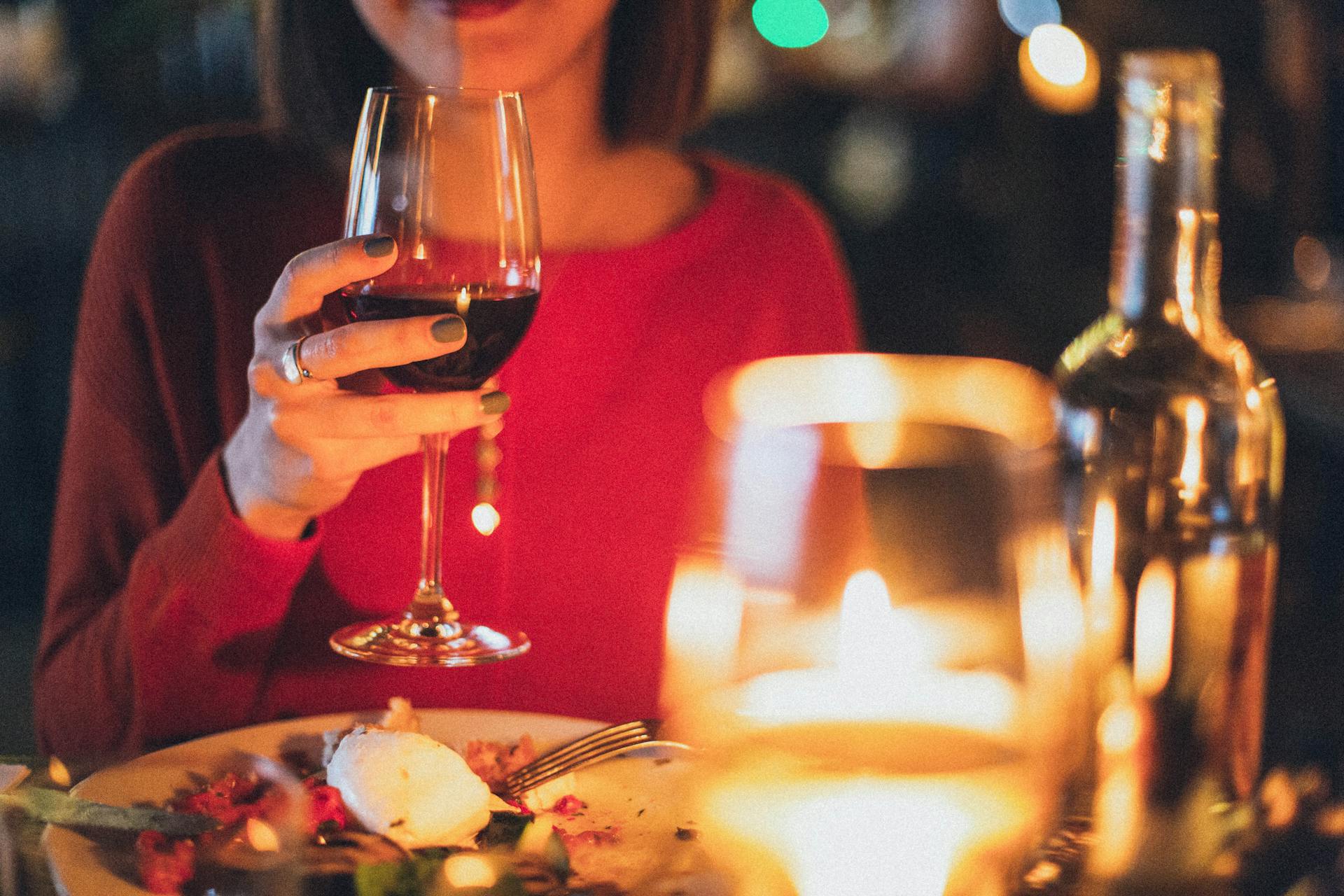 Primer plano de una mujer con una copa de vino en la mano durante la cena | Fuente: Pexels