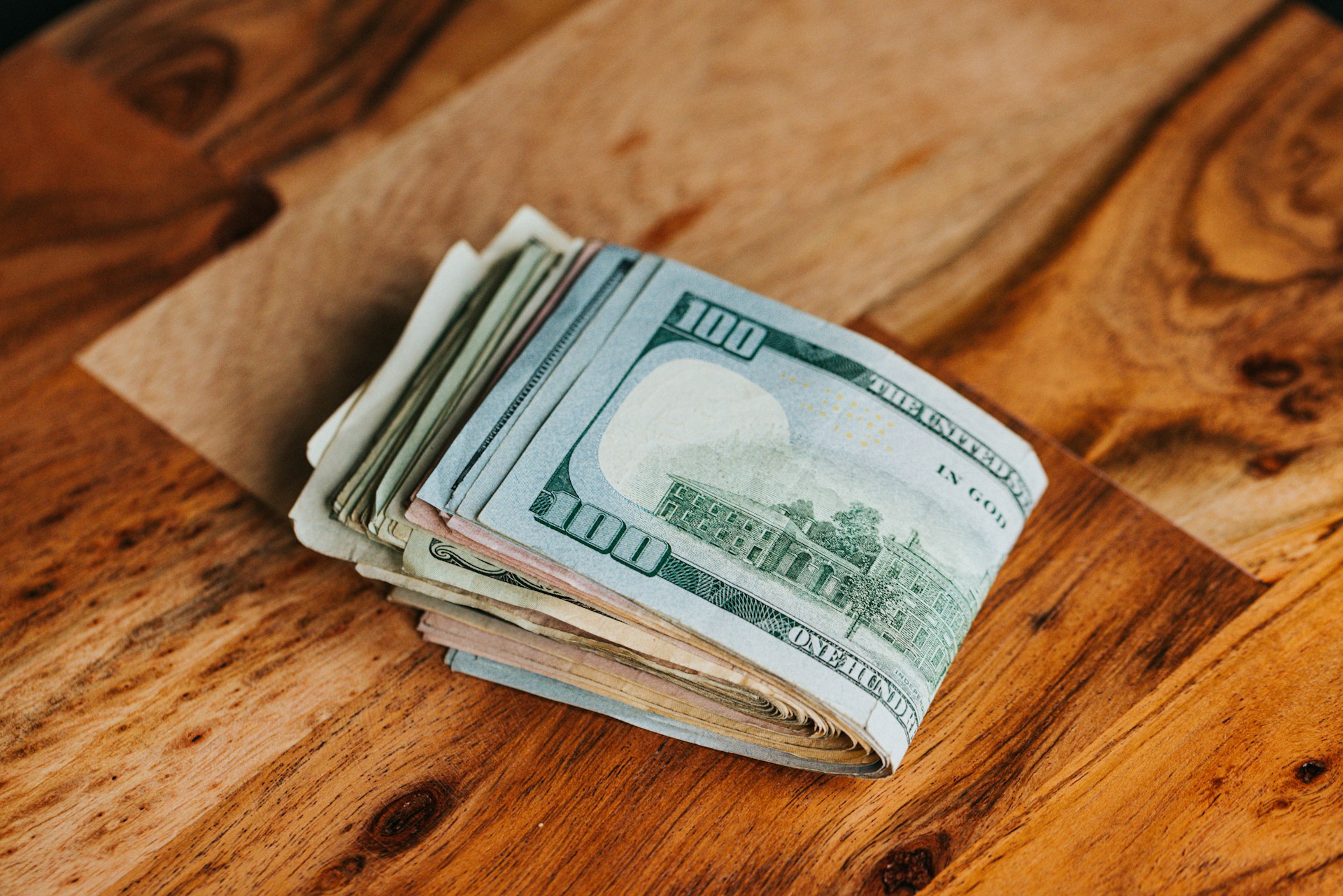 Billetes de dólar sobre una superficie de madera | Fuente: Unsplash