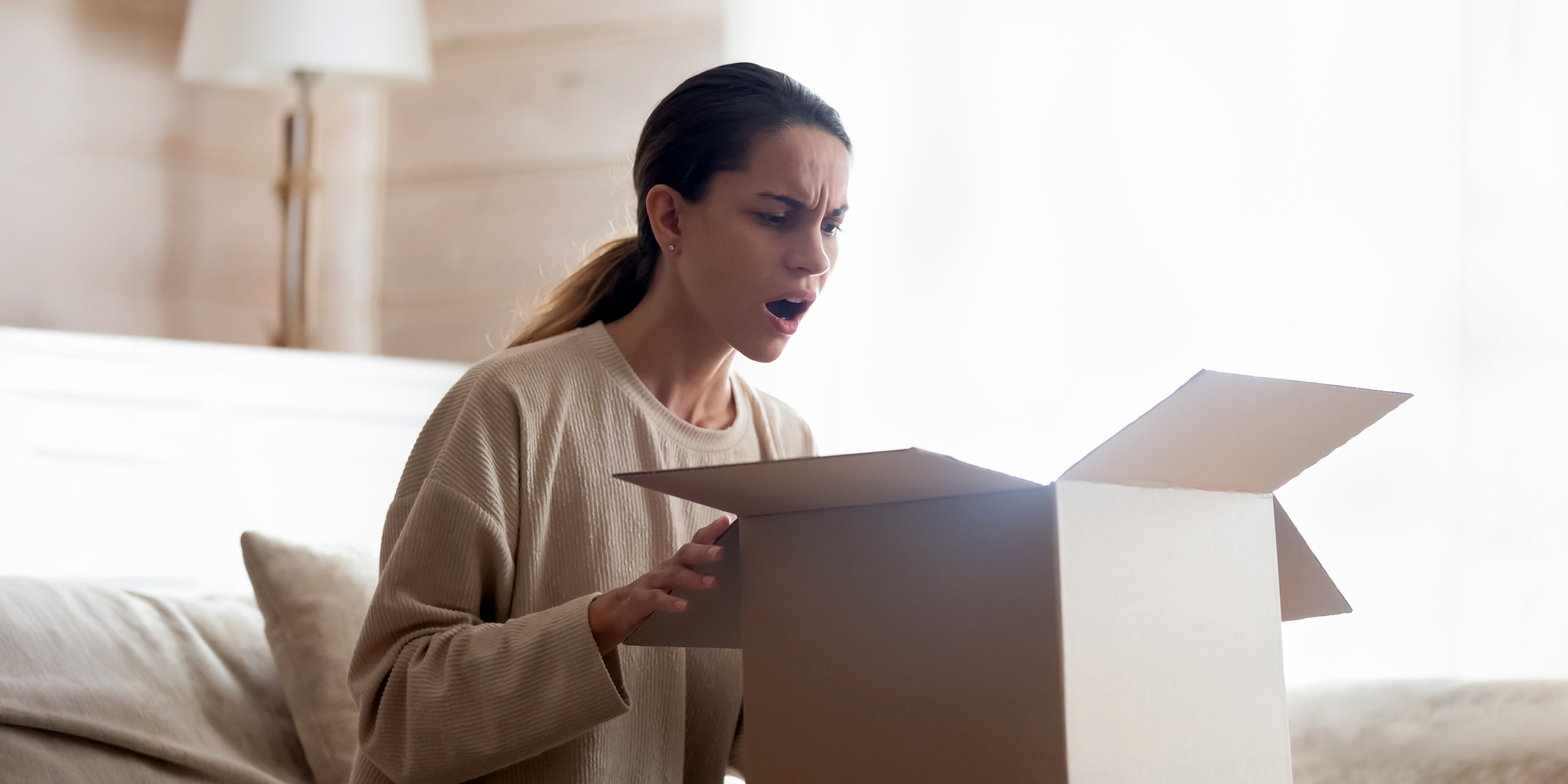 Mujer abriendo una caja con incredulidad | Fuente: Shutterstock