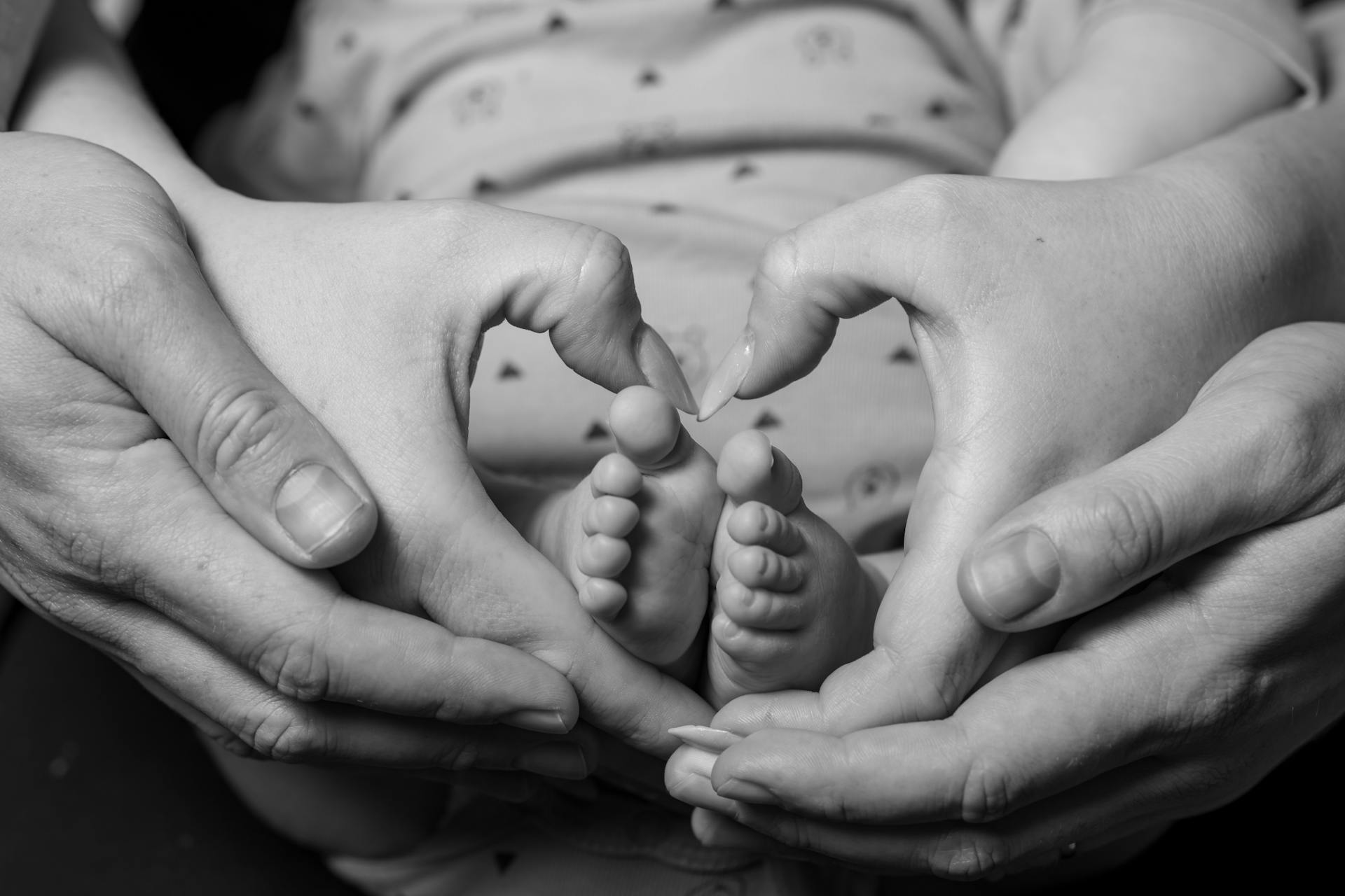 Una pareja haciendo una señal en forma de corazón alrededor de los pies de su bebé | Fuente: Pexels