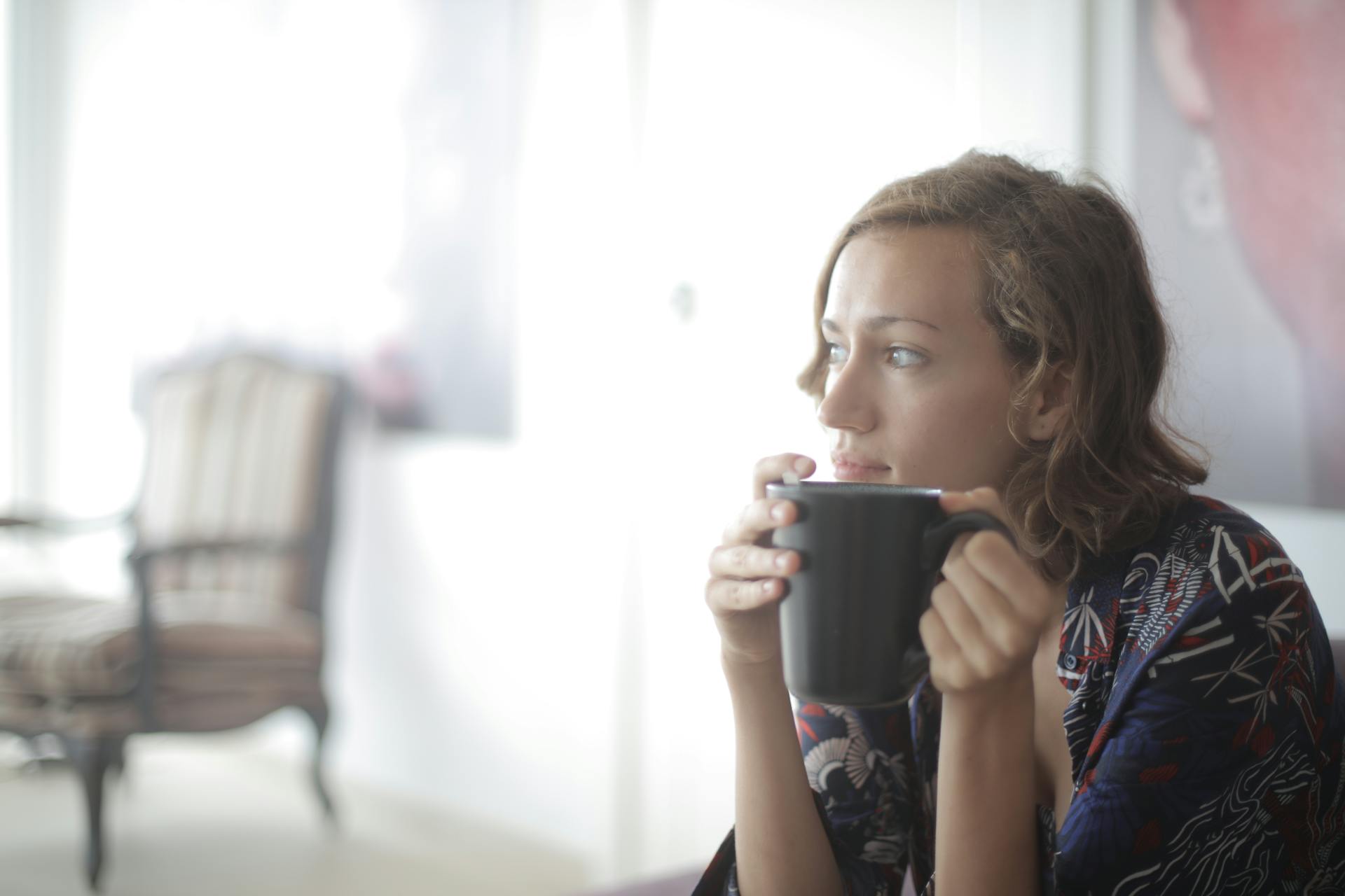Una mujer tomando algo caliente en un salón | Fuente: Pexels