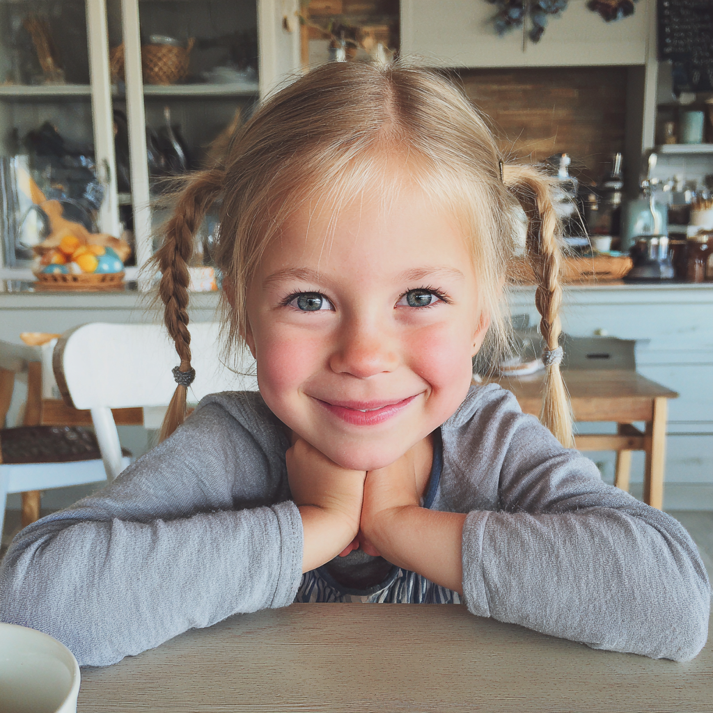 Una niña sonriente sentada a la mesa del desayuno | Fuente: Midjourney