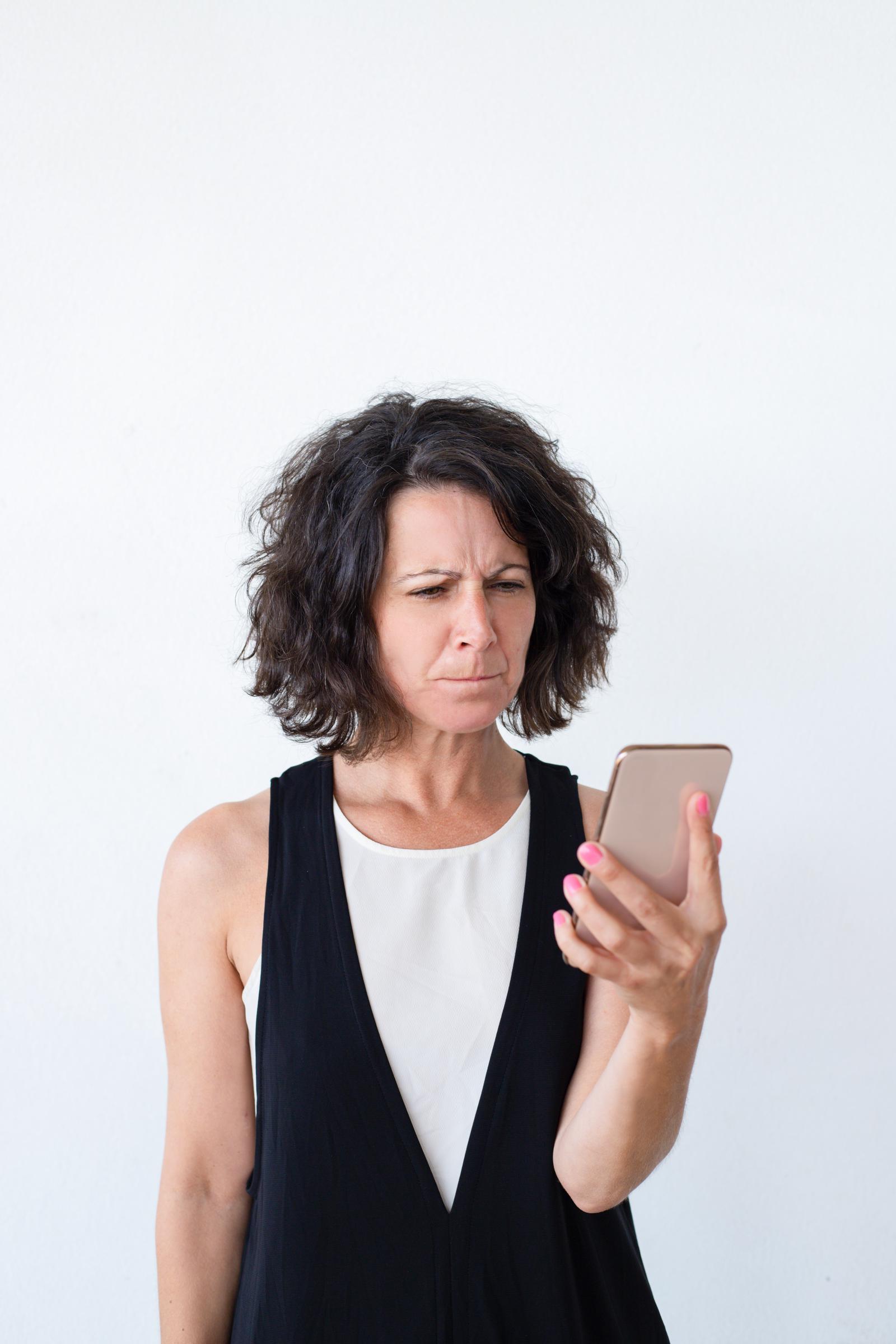 Una mujer molesta mirando su teléfono | Fuente: Freepik