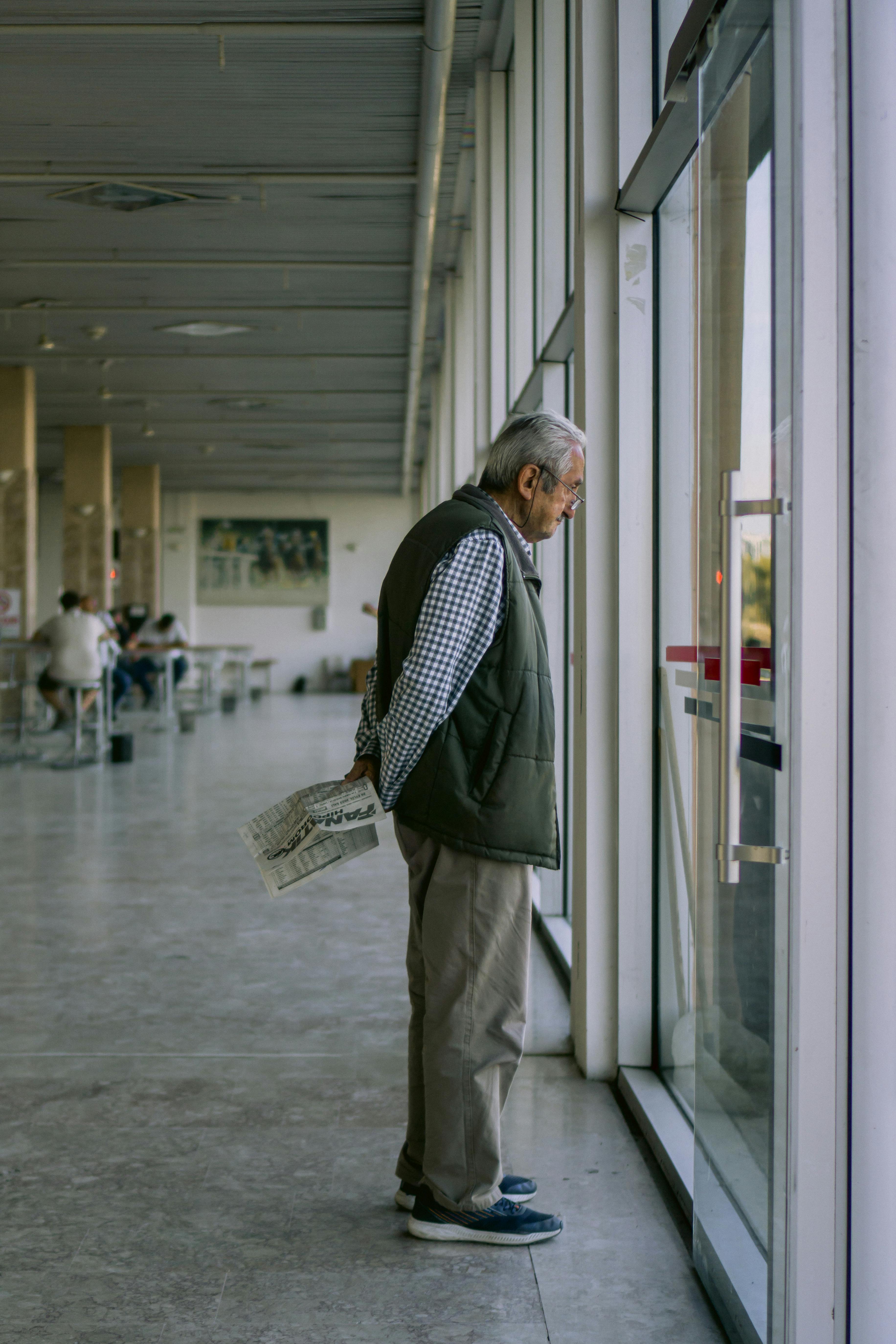 Hombre mayor mirando por la ventanilla en un aeropuerto | Fuente: Pexels