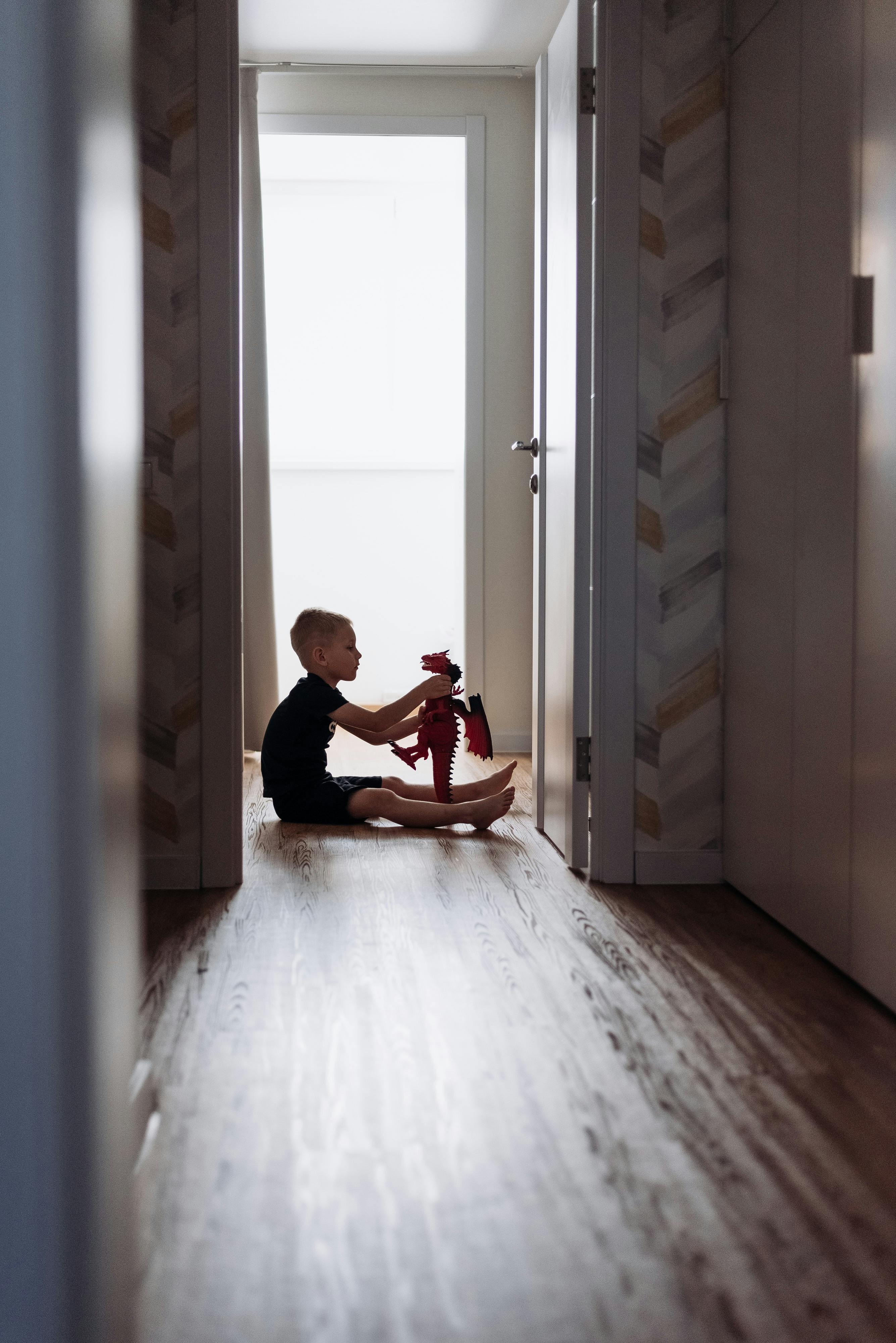 Un niño sentado en el suelo jugando con un juguete | Fuente: Pexels