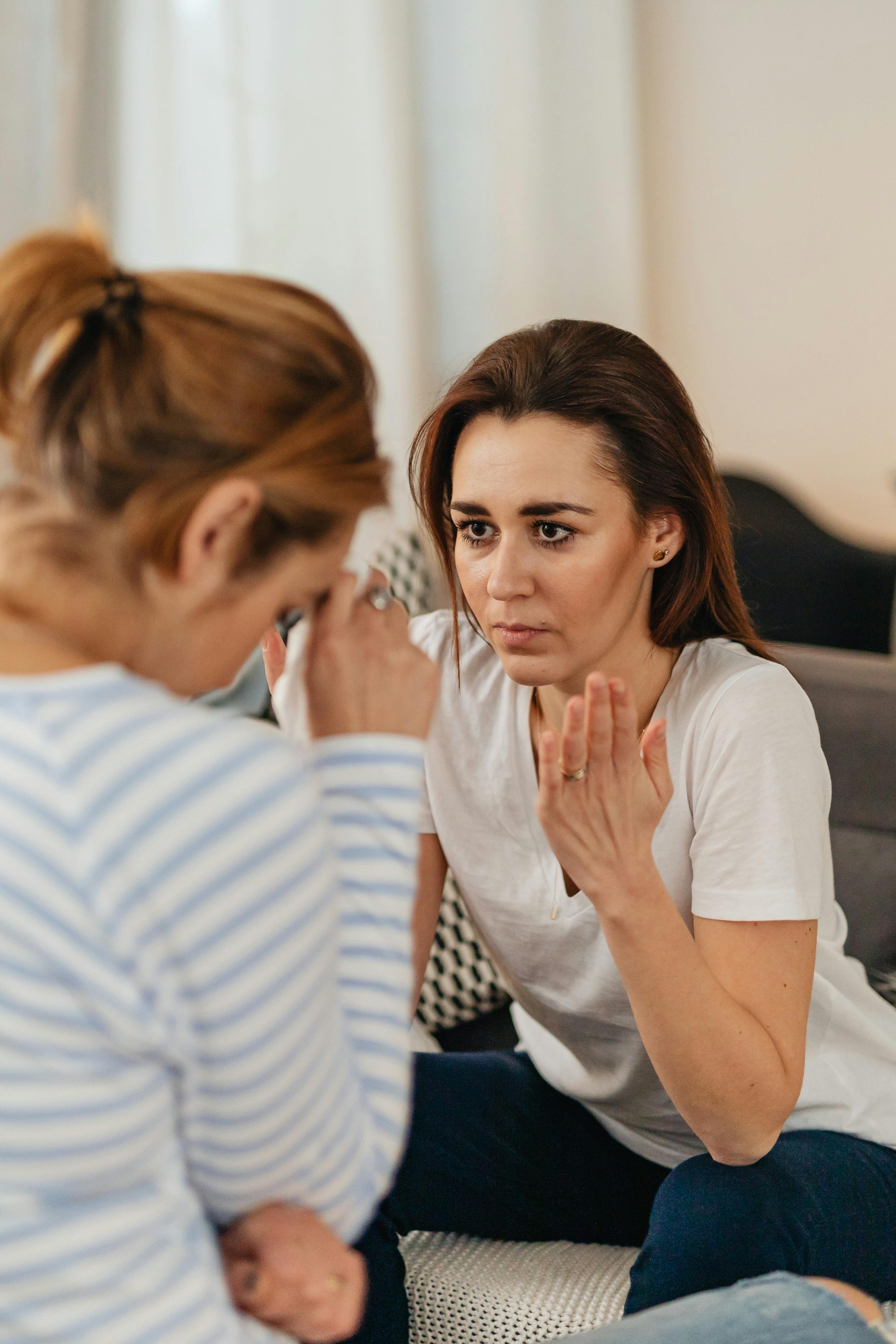 Una mujer hablando mientras otra tiene la cara gacha | Fuente: Pexels
