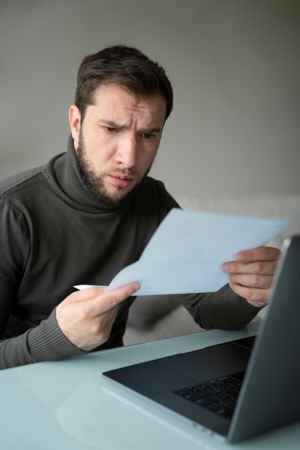 Un hombre aturdido mirando una hoja de papel | Fuente: Freepik