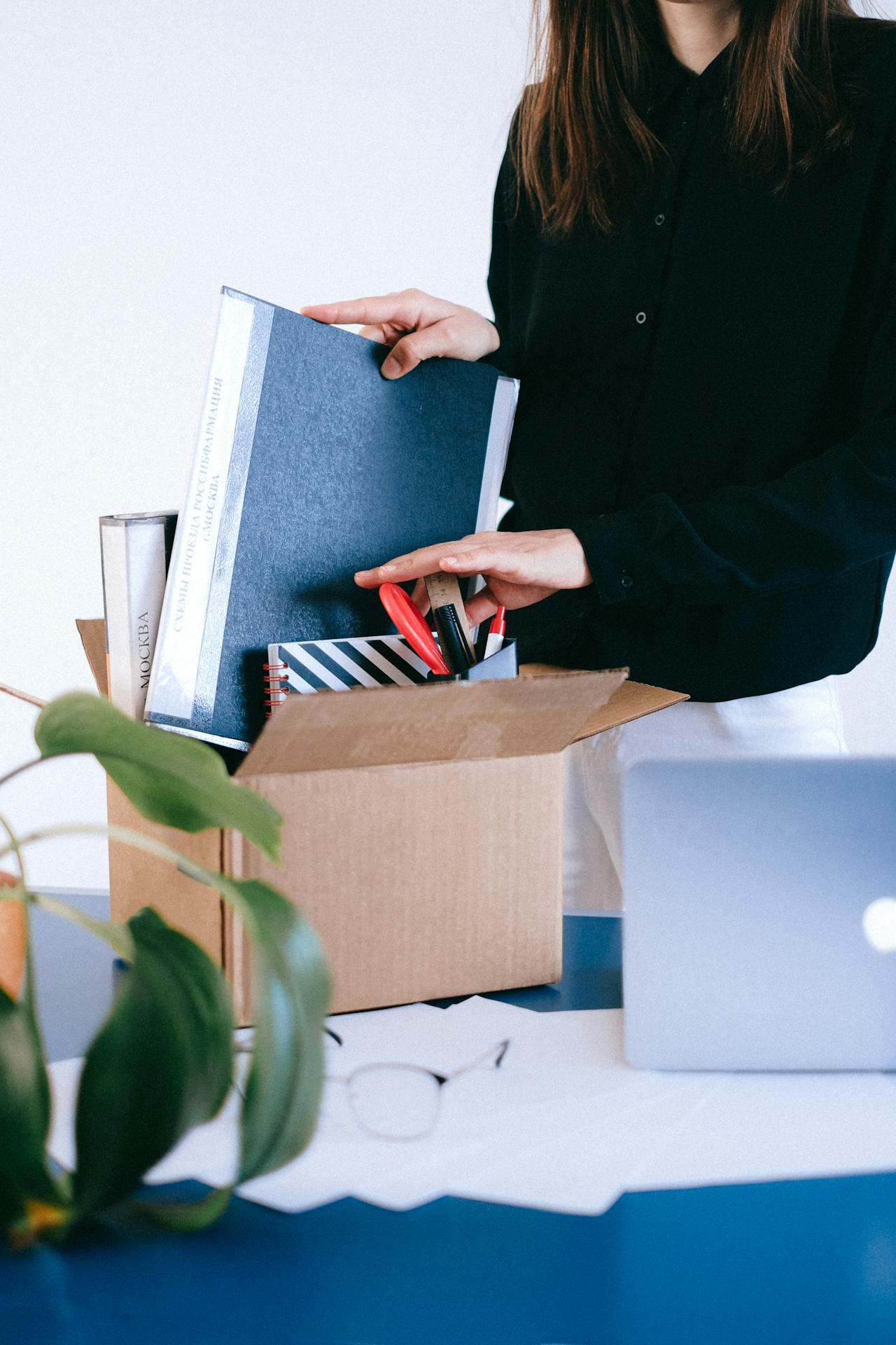 Una mujer organizando material de oficina en una caja | Fuente: Pexels