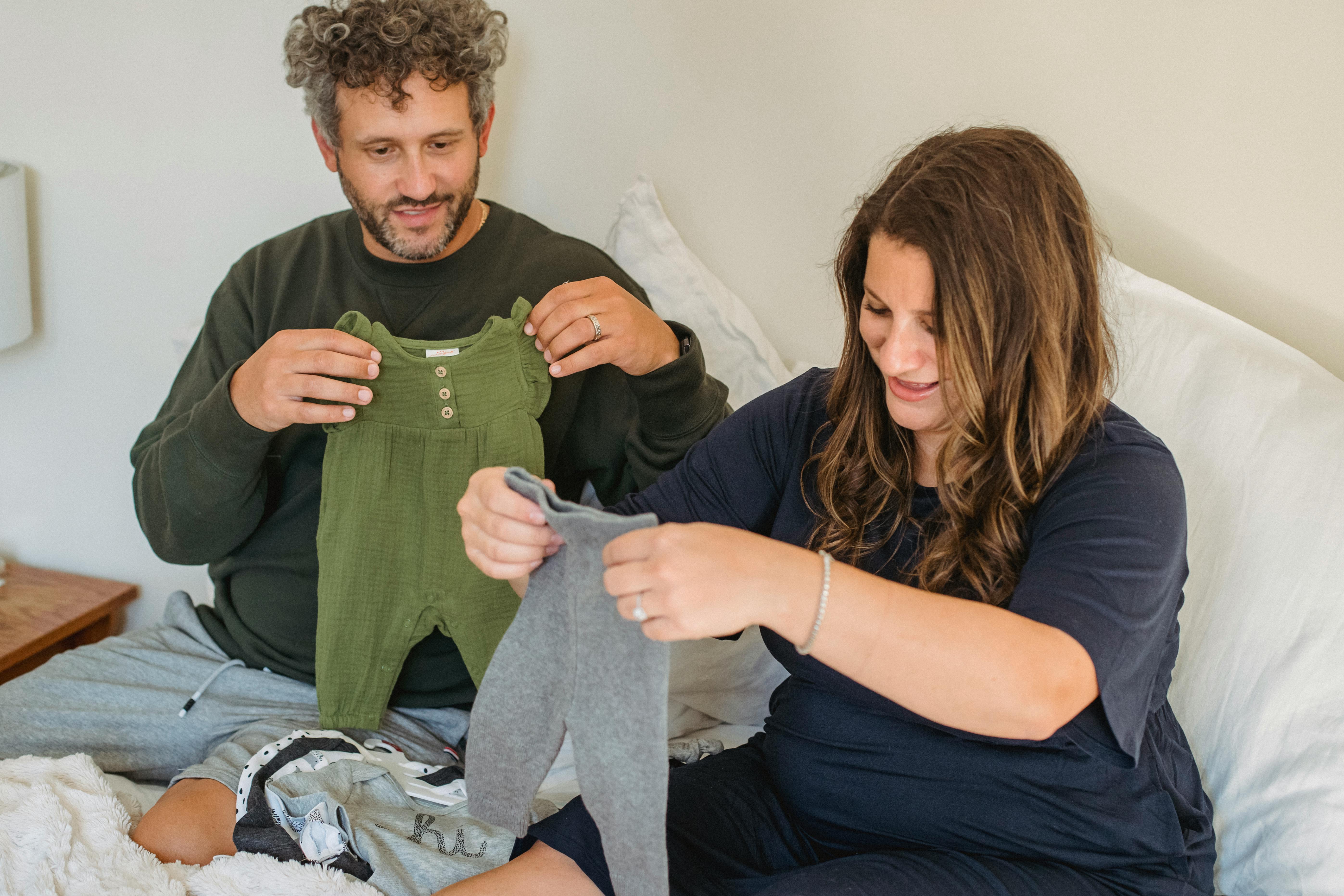 Una pareja viendo ropa de bebé | Fuente: Pexels