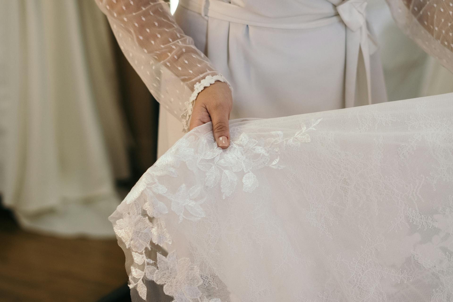 Una mujer sujetando un vestido de novia de encaje | Fuente: Pexels
