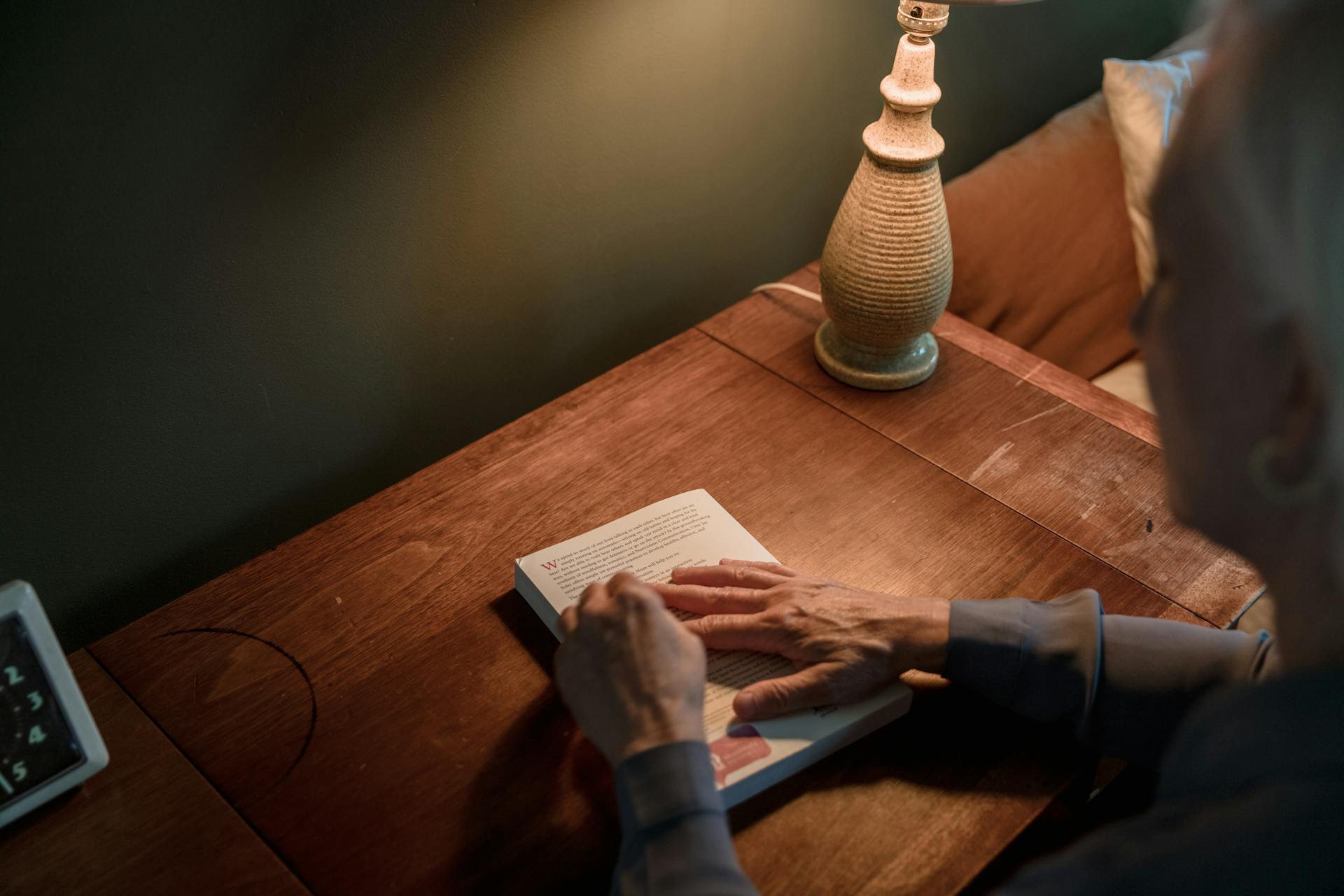 Una mujer mayor sosteniendo un libro encima de un escritorio | Fuente: Pexels