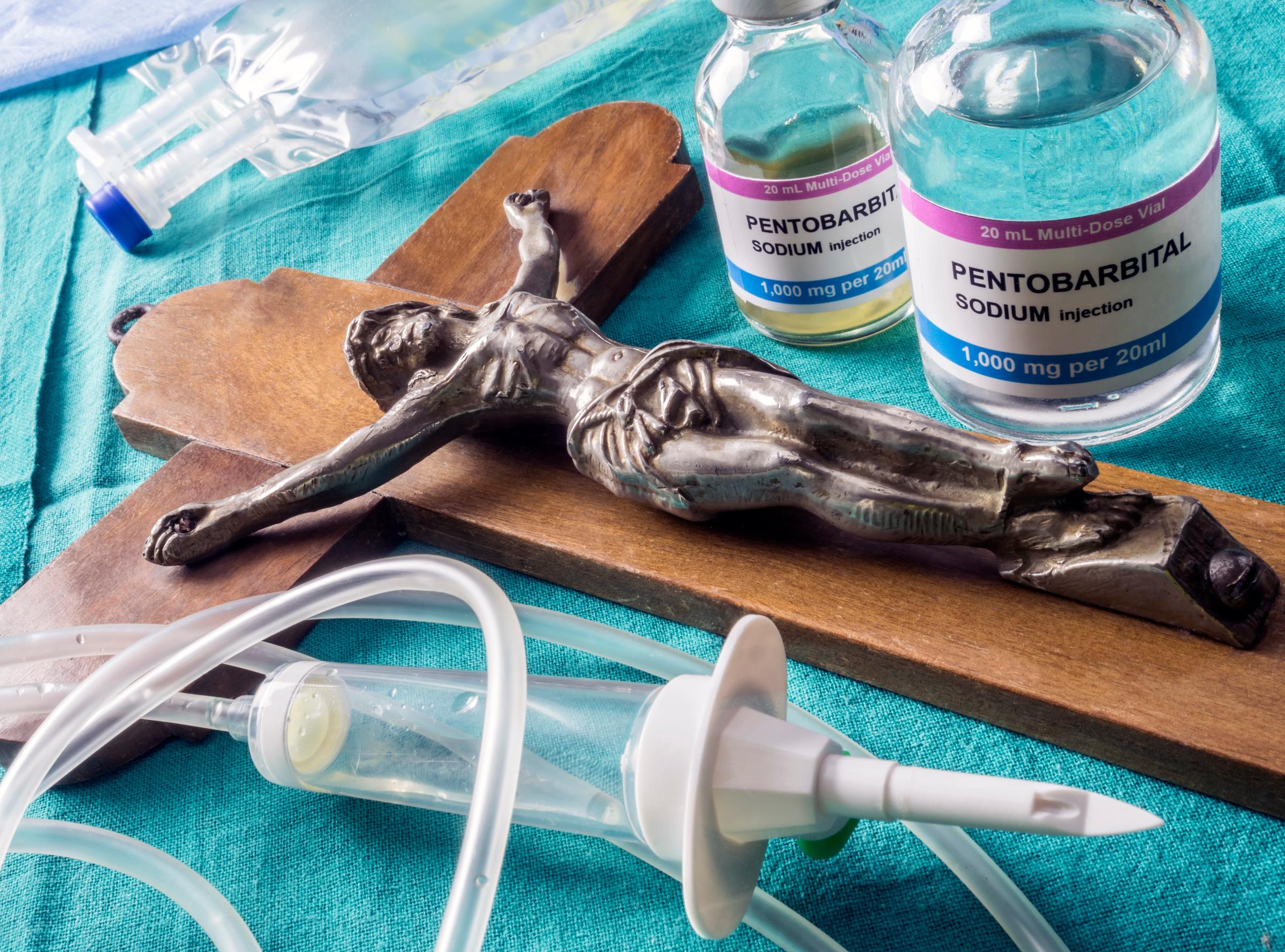 Frasco con dosis de un medicamento, junto a un crucifijo. | Fuente: Shutterstcok.