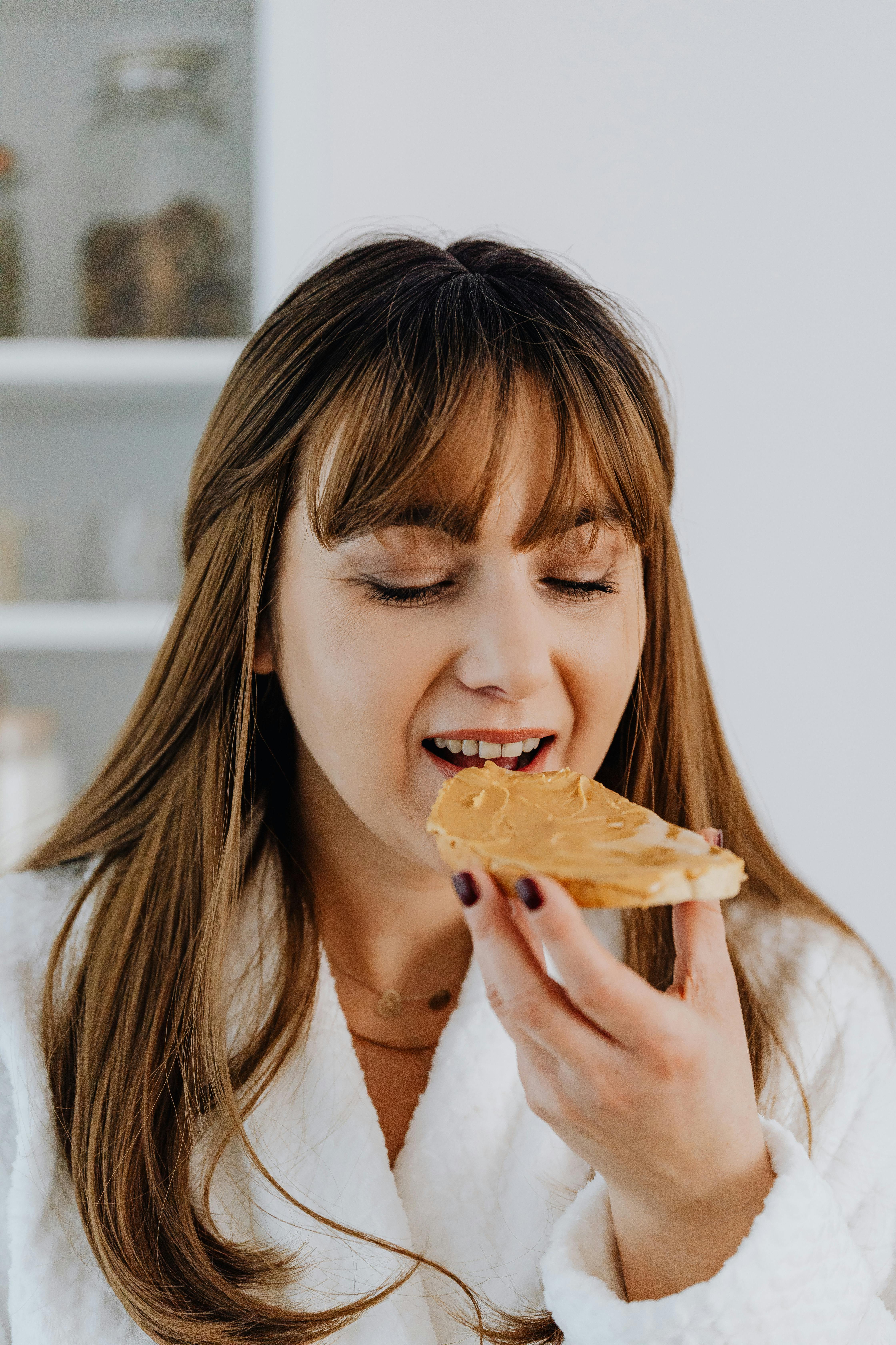 Una mujer comiendo un bocadillo de mantequilla de cacahuete | Fuente: Pexels