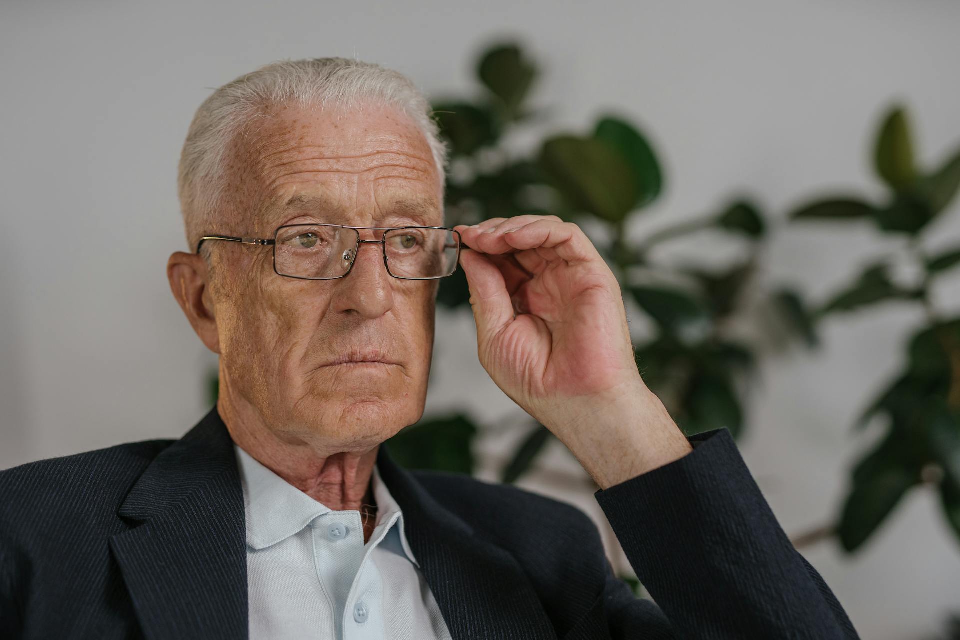 Un hombre mayor sujetando sus gafas | Fuente: Pexels