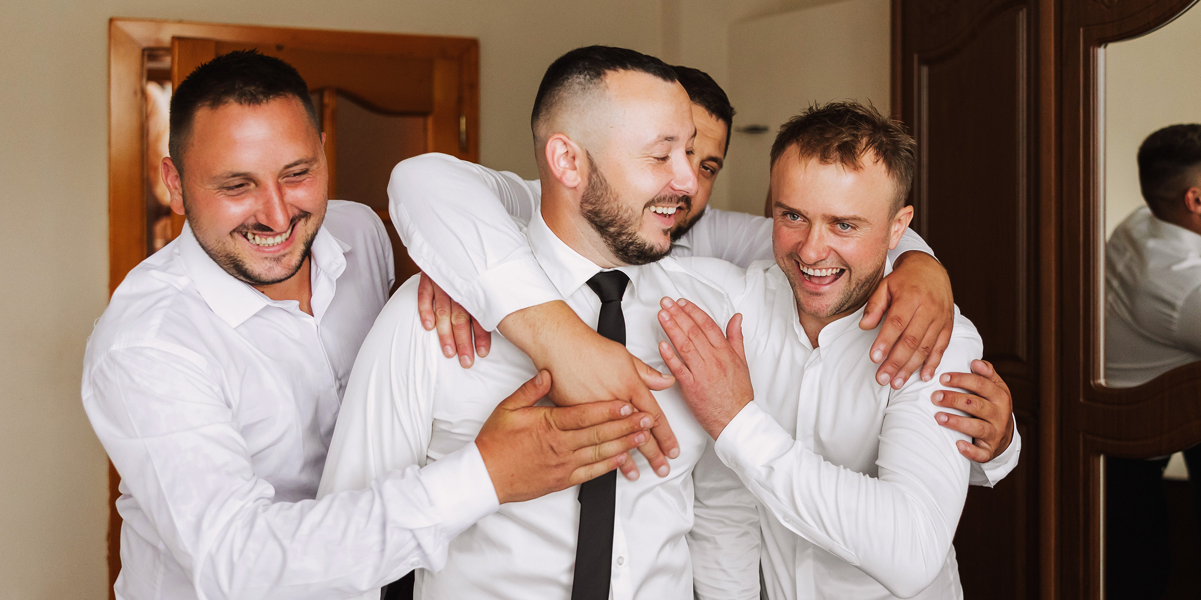 Un novio riendo con sus padrinos | Fuente: Shutterstock