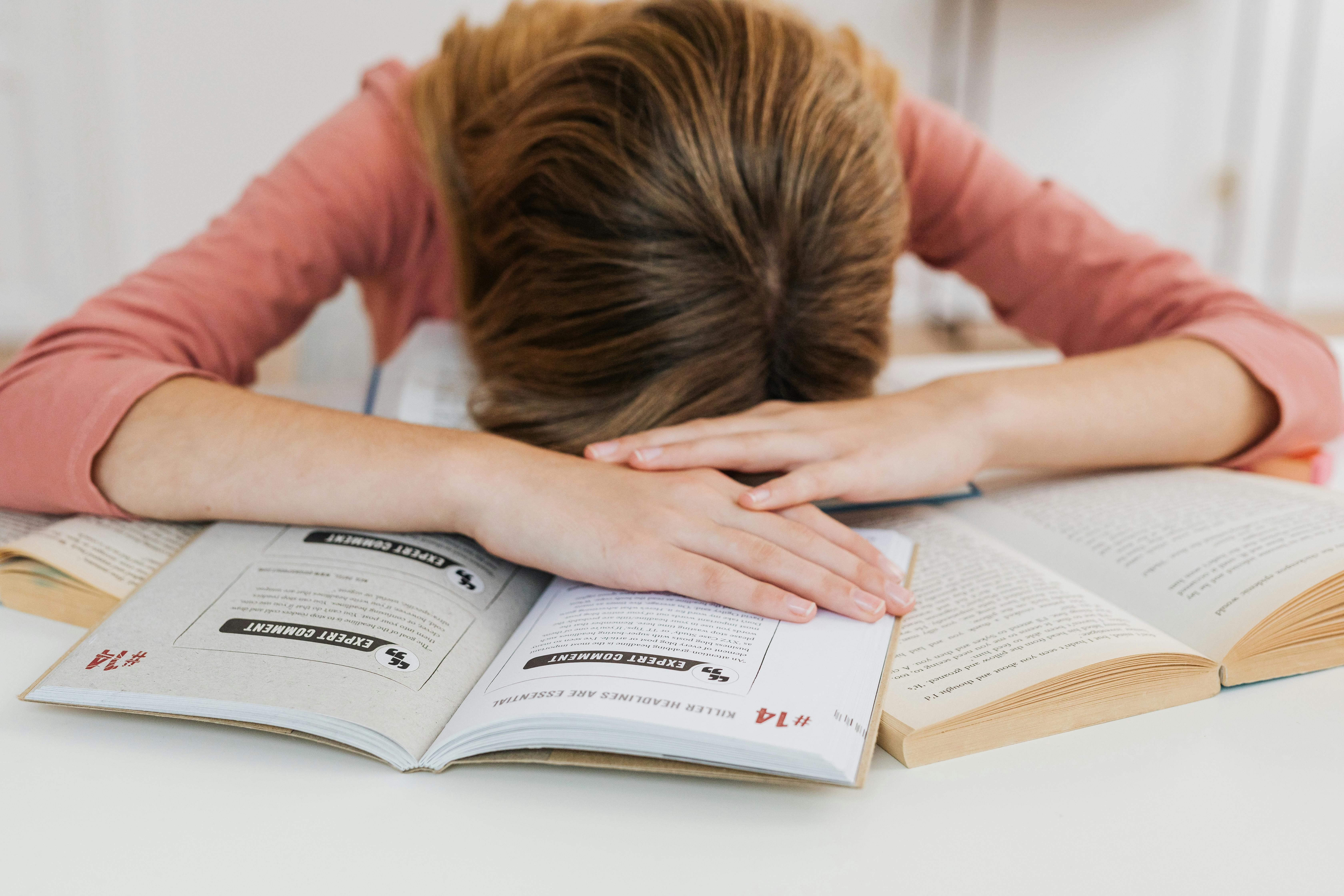 Una chica estresada tumbada sobre sus libros | Fuente: Pexels