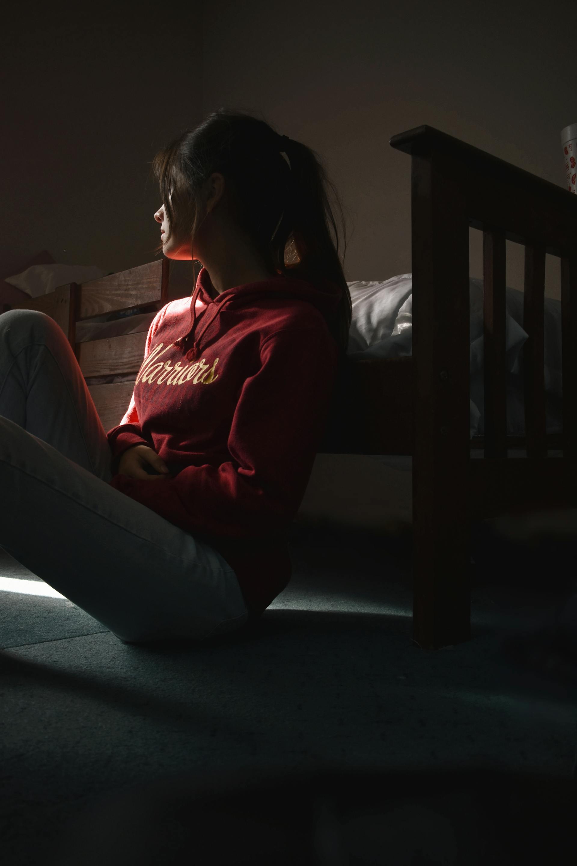 Una mujer joven sentada en el suelo y mirando de reojo | Fuente: Pexels