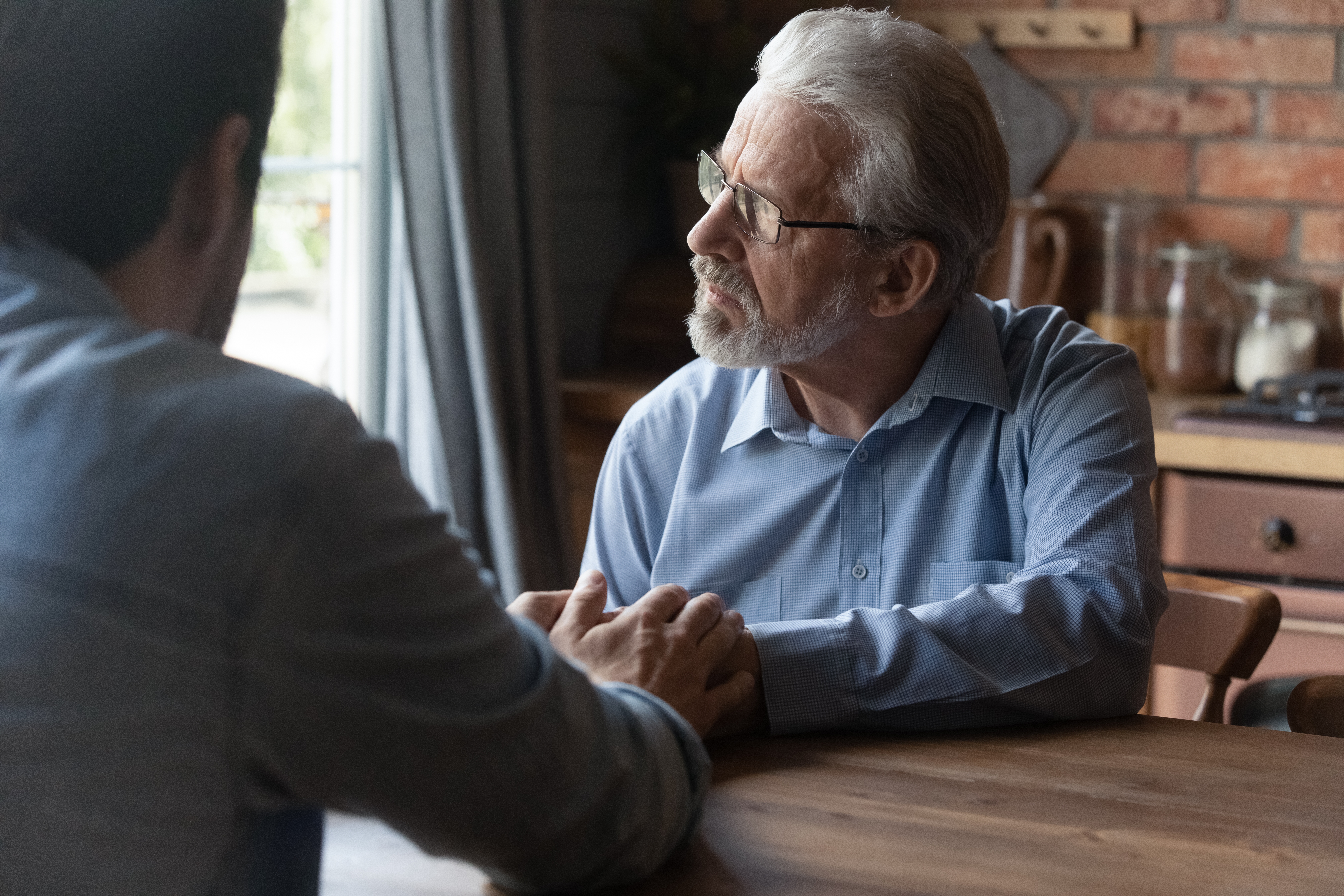 Un hijo adulto sentado con su padre estresado | Fuente: Shutterstock