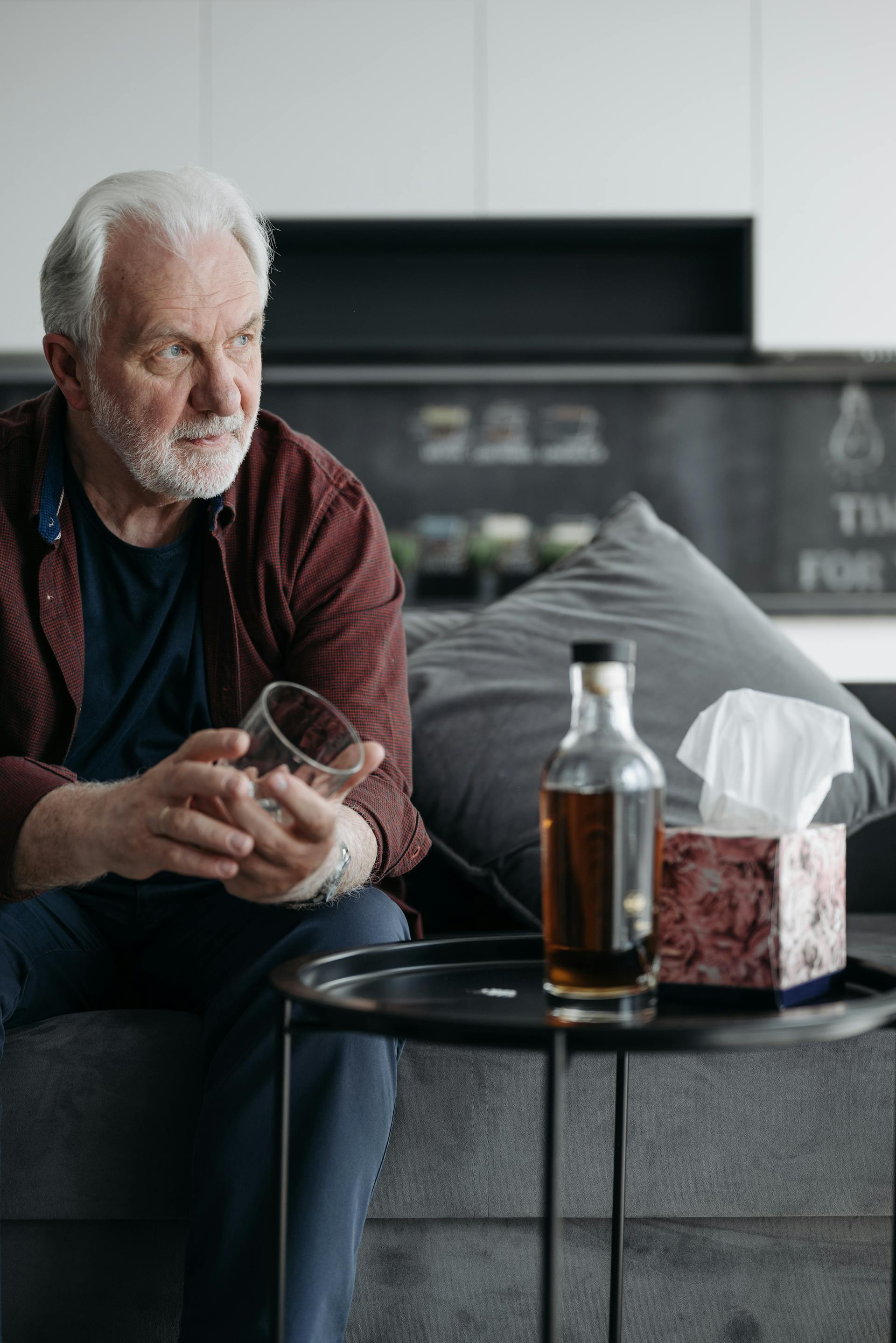 Un hombre sostiene un vaso con una botella de cerveza delante | Fuente: Pexels