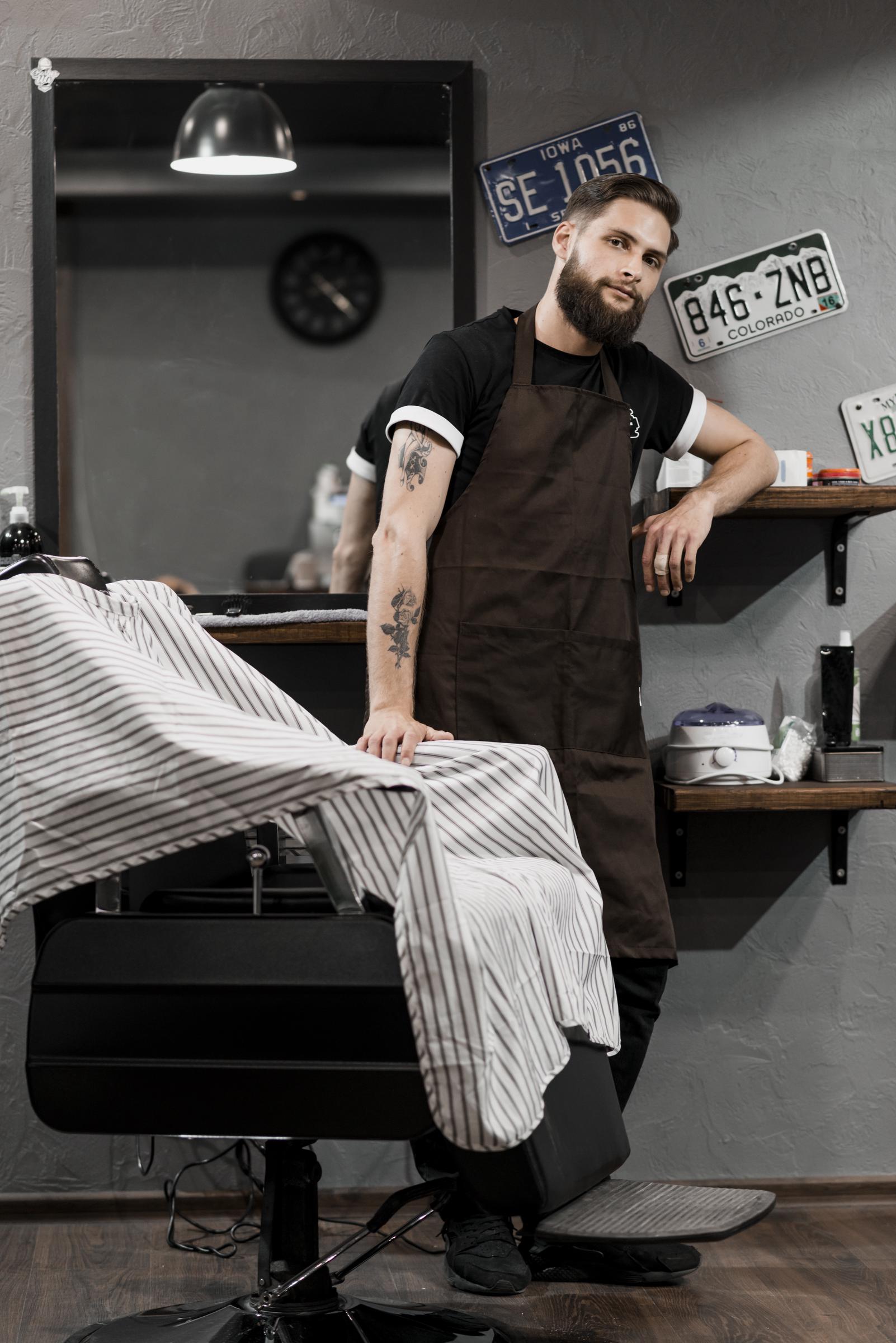 Un peluquero de pie en una barbería | Fuente: Freepik