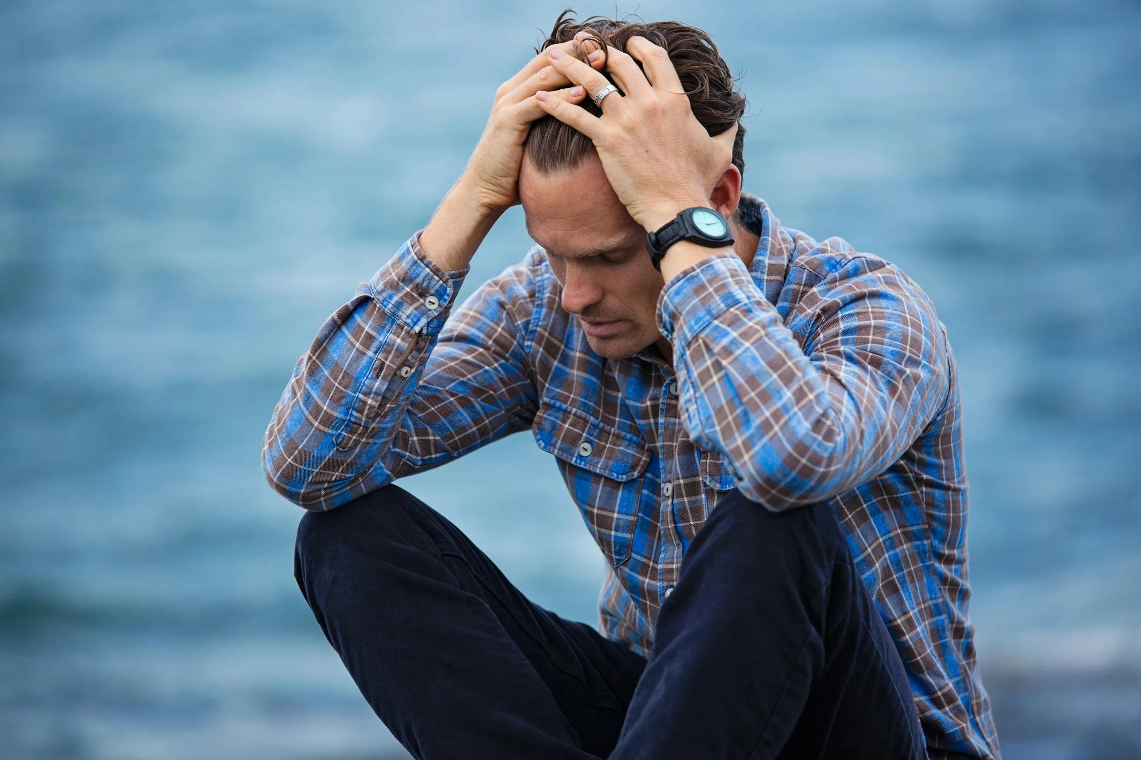 Un hombre triste sentado junto al mar | Fuente: Pexels