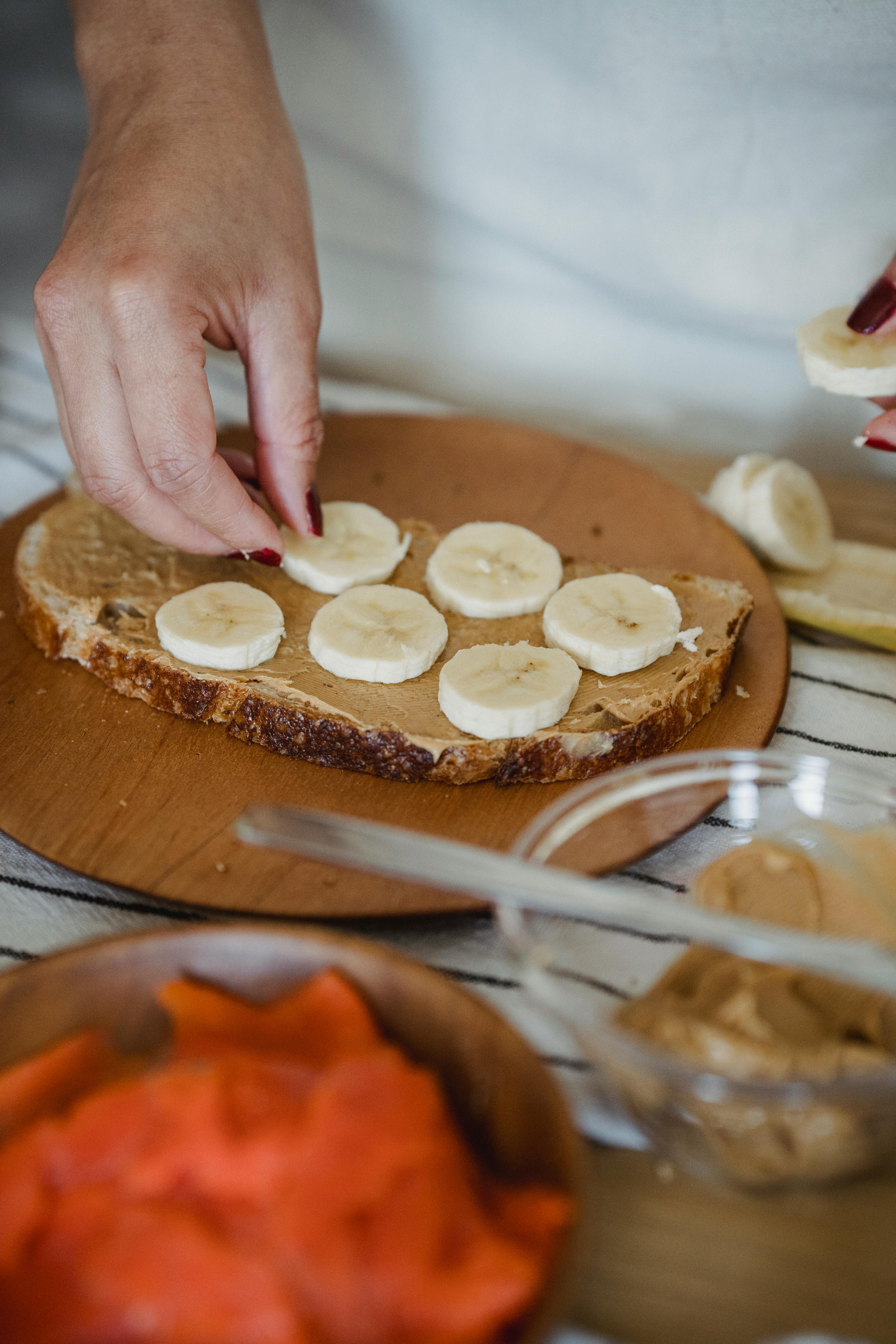 Una mujer preparando un sándwich de mantequilla de cacahuete y plátano | Fuente: Pexels