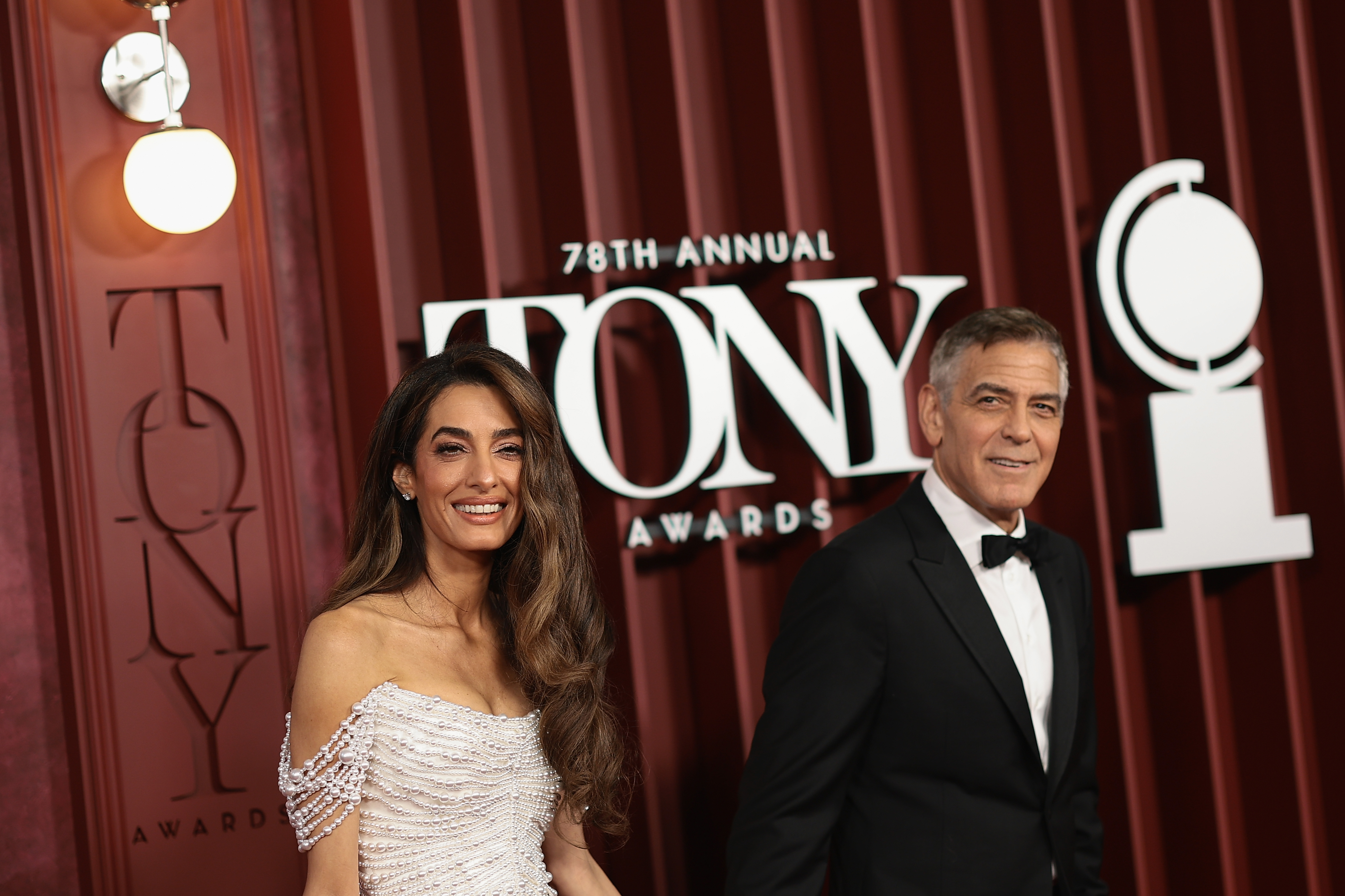 George y Amal Clooney sonríen codo con codo mientras posan junto al cartel de la 78.ª edición de los Premios Tony. La presencia segura de la pareja añade un toque de encanto hollywoodiense a la gran noche de Broadway.