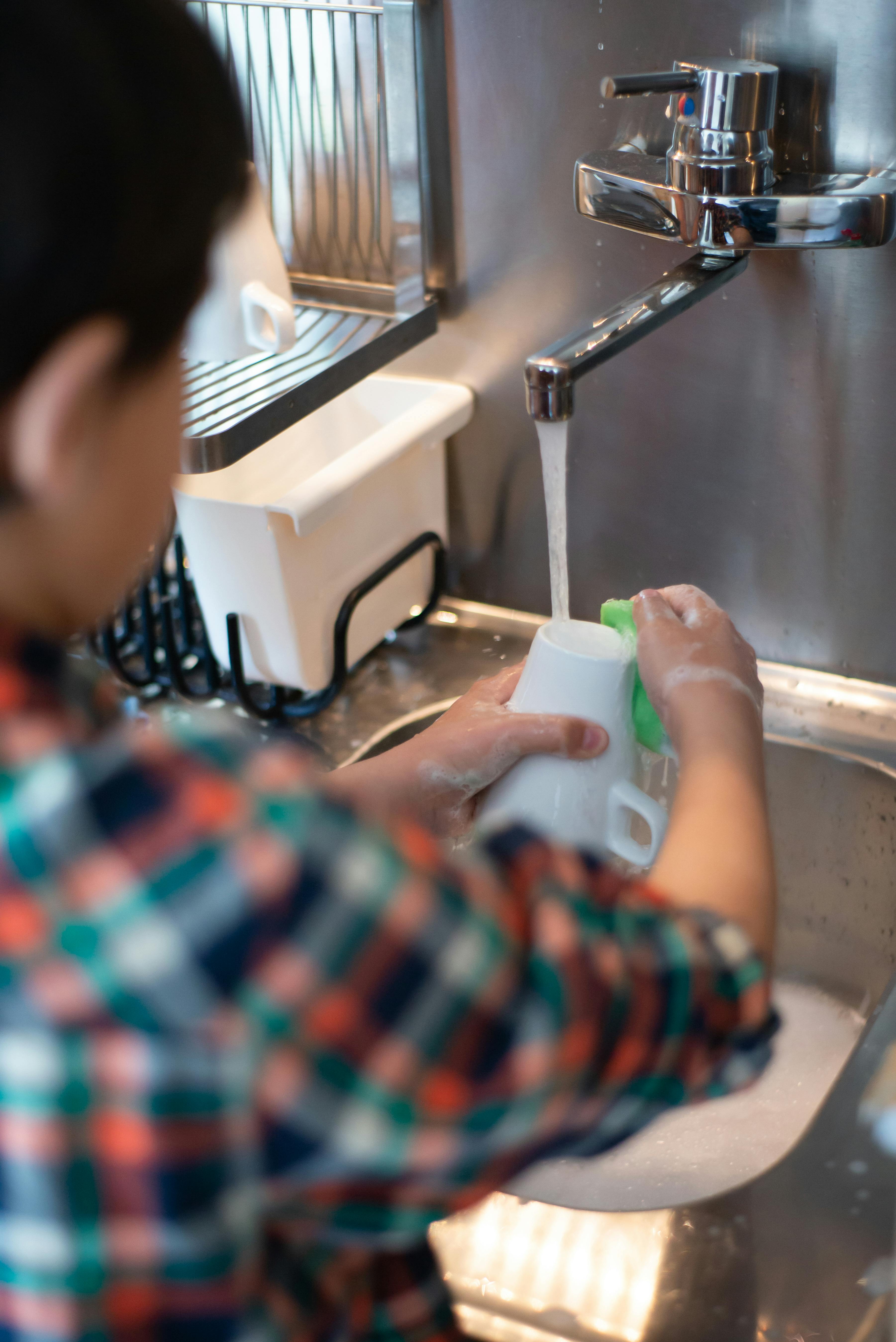 Niño lavando una taza | Fuente: Pexels