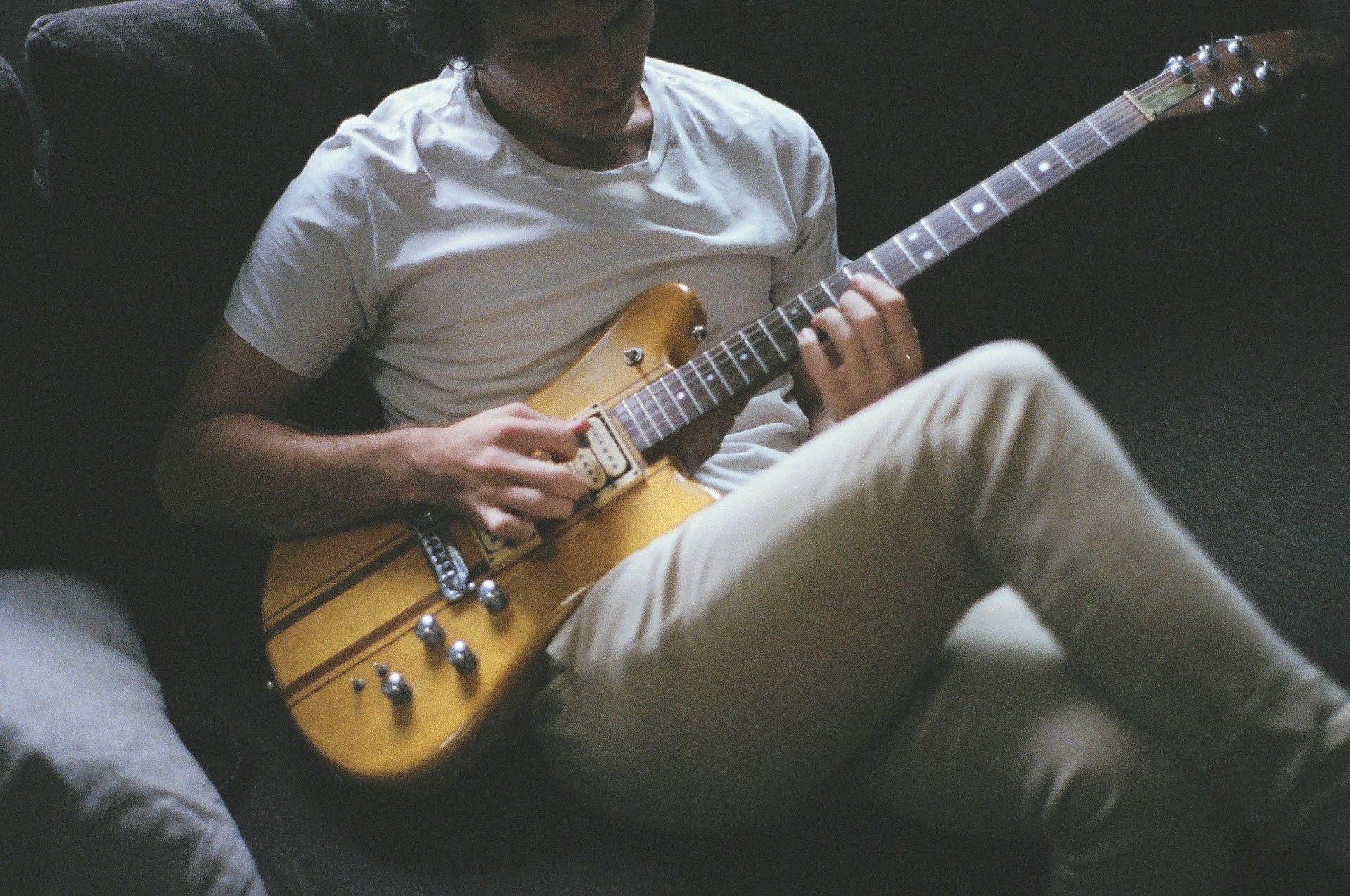 Un hombre tocando una guitarra eléctrica en un sofá | Fuente: Unsplash