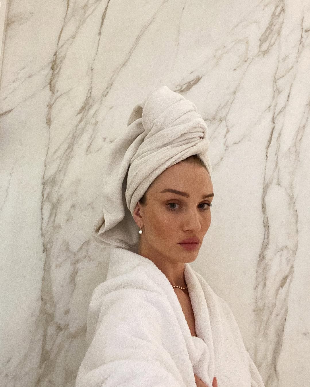 Rosie Huntington-Whiteley posa en un sereno cuarto de baño de mármol, envuelta en un albornoz blanco de felpa con un turbante de toalla a juego. | Fuente: Instagram/rosiehw