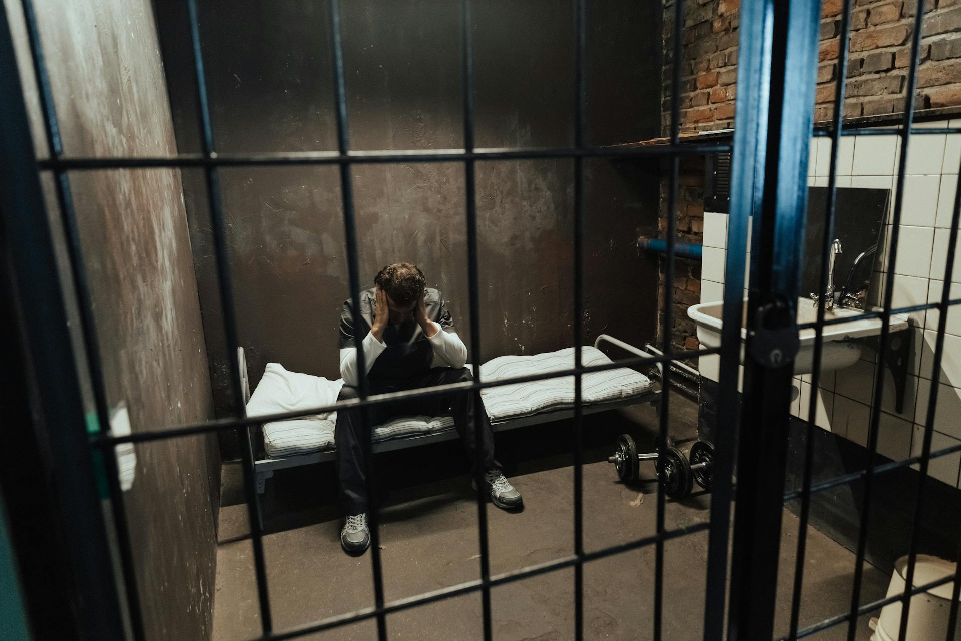 Un hombre sentado en una cama entre rejas | Fuente: Pexels
