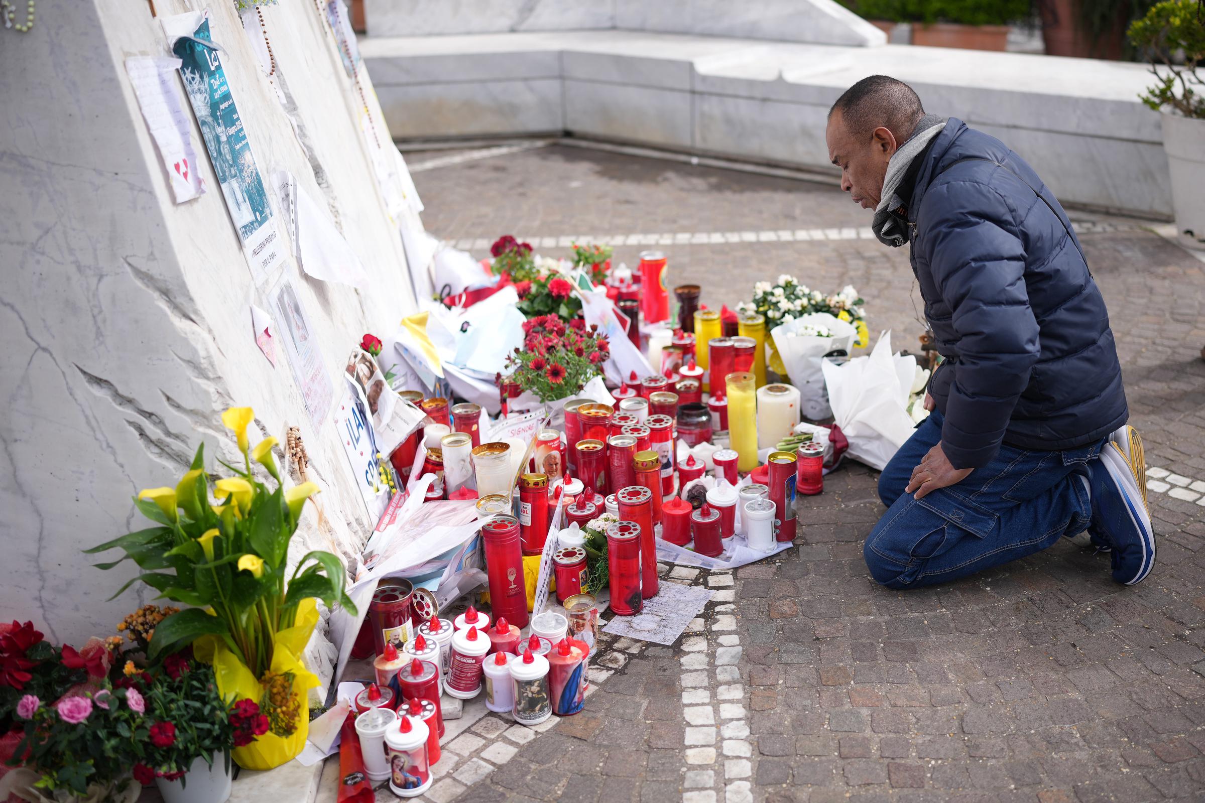 Un hombre reza bajo la escultura de San Juan Pablo II en la entrada principal del Hospital Policlínico A. Gemelli, donde se atendía al papa Francisco, en Roma, Italia, el 13 de marzo de 2025 | Fuente: Getty Images