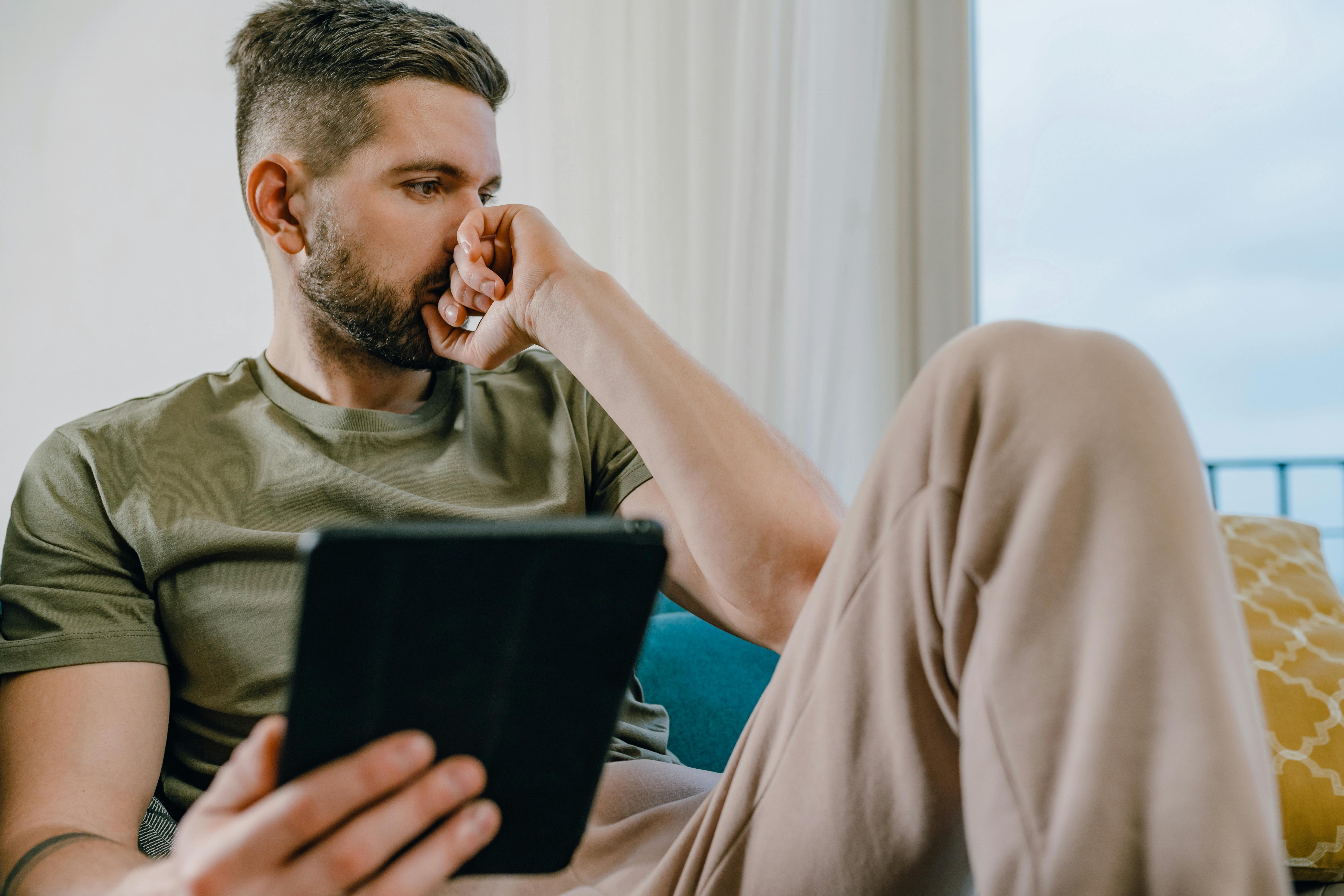Un hombre sumido en sus pensamientos sosteniendo una tableta | Fuente: Pexels