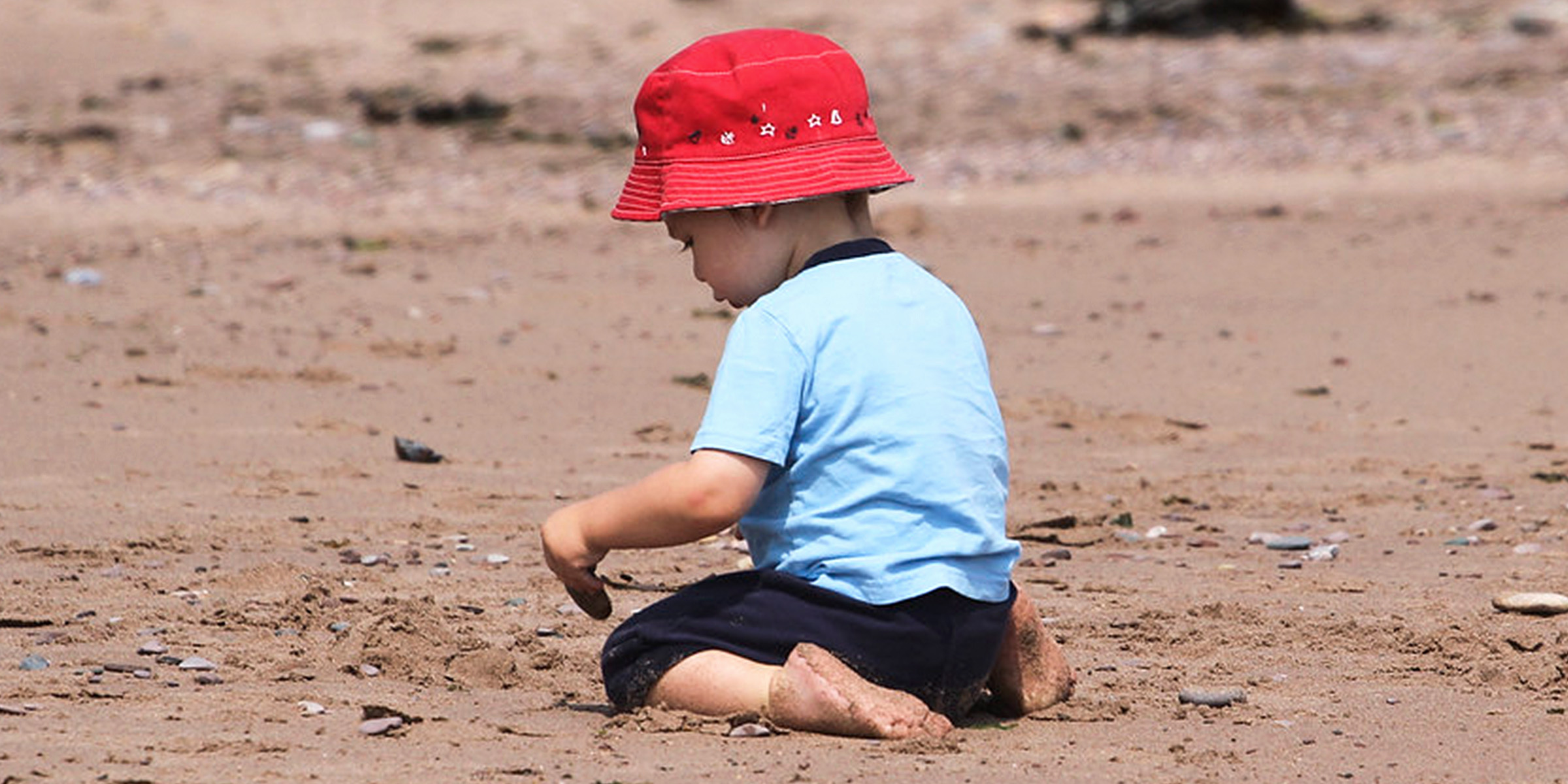 Un niño sentado en la arena | Fuente: Flickr